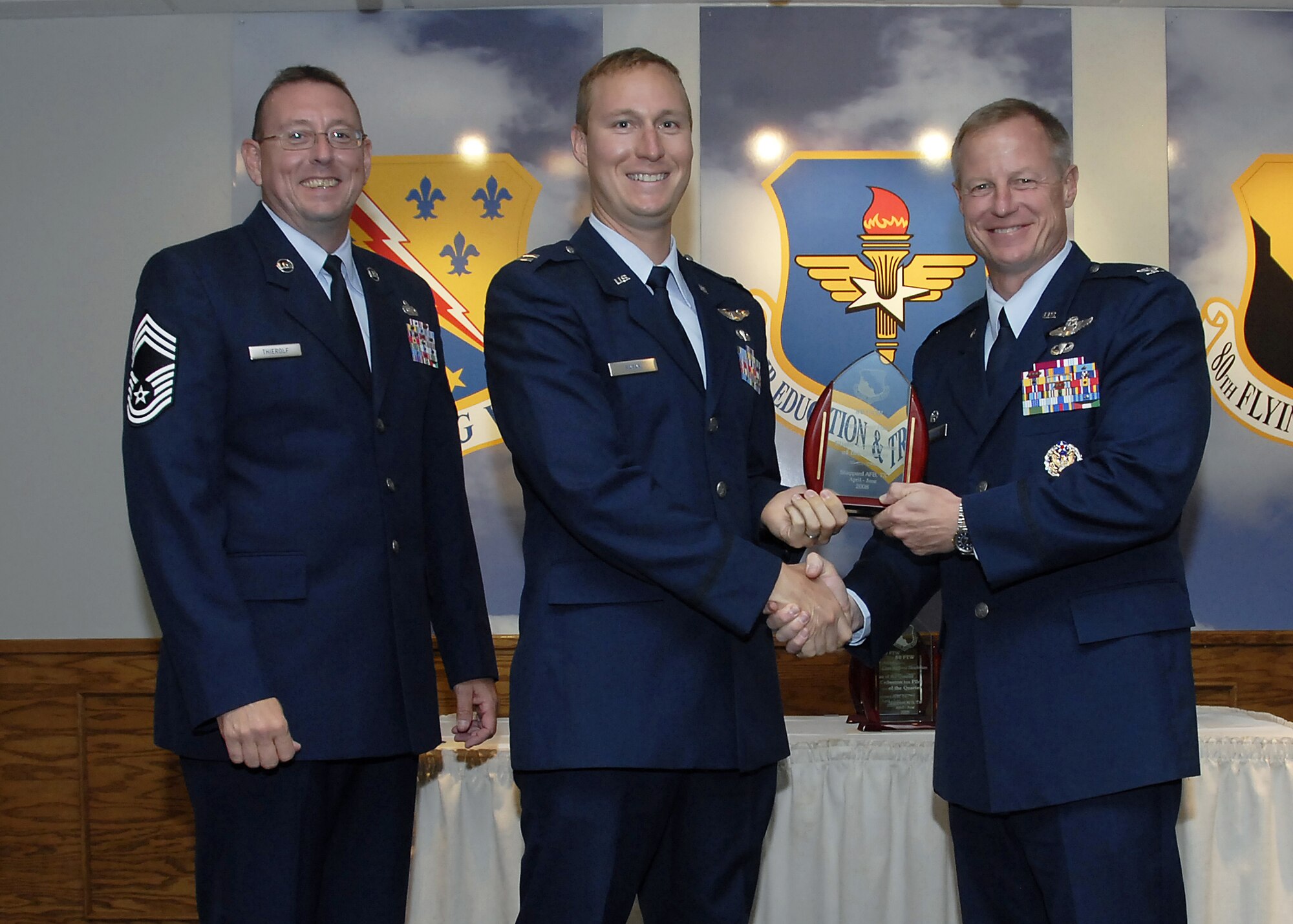 Capt. Daniel Patak, center, accepts the Flight Commander of the Quarter award from 80th Flying Training Wing Commander David Petersen July 22 at the wing's quarterly awards banquet. Also pictured is wing Superintendent Chief Master Sgt. Norman Thierolf. (U.S. Air Force photo/Mike Litteken)