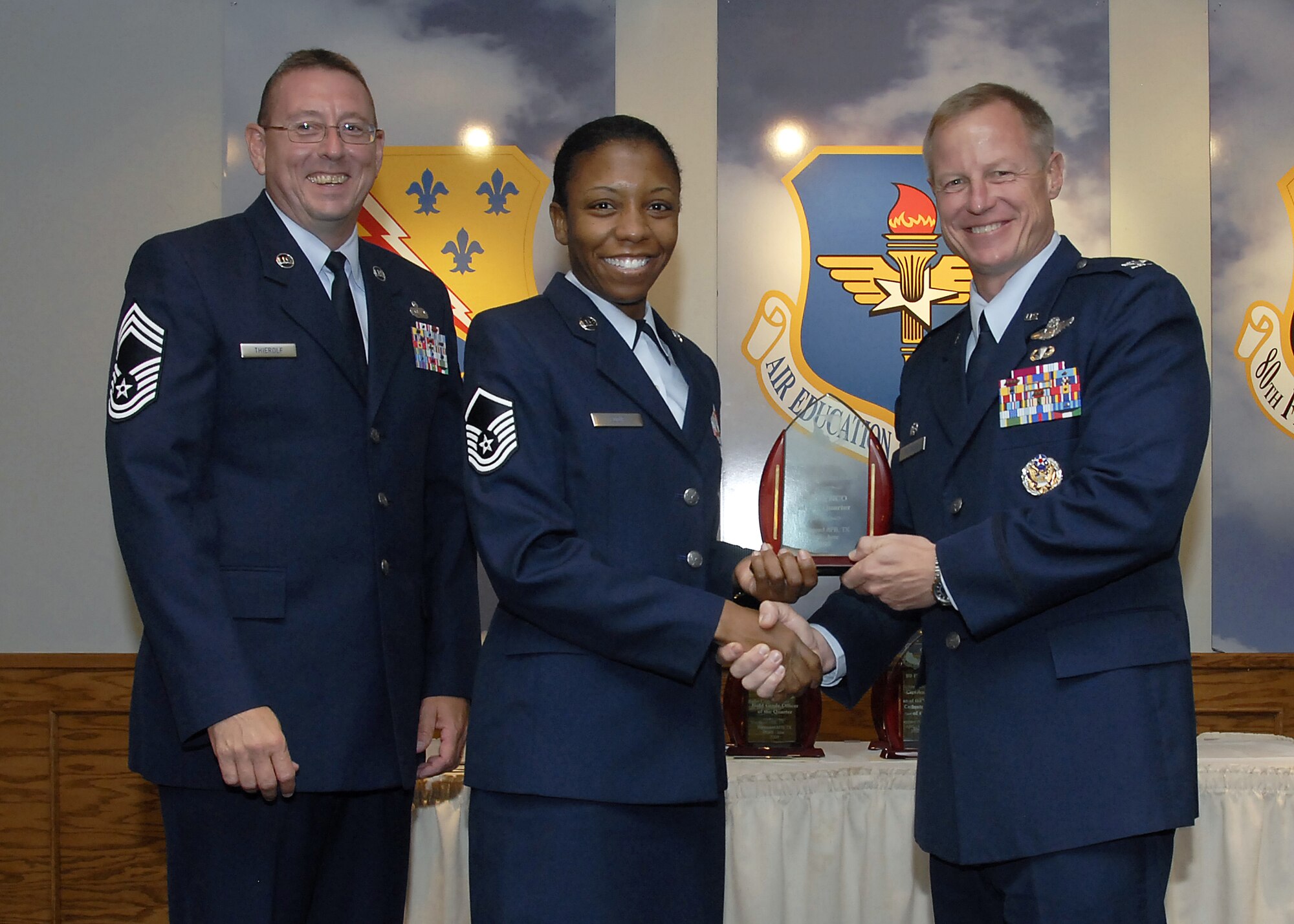 Master Sgt. Veronica Eddie, center, accepts the Senior Noncommissioned Officer of the Quarter award from 80th Flying Training Wing Commander David Petersen July 22 at the wing's quarterly awards banquet. Also pictured is wing Superintendent Chief Master Sgt. Norman Thierolf. (U.S. Air Force photo/Mike Litteken)