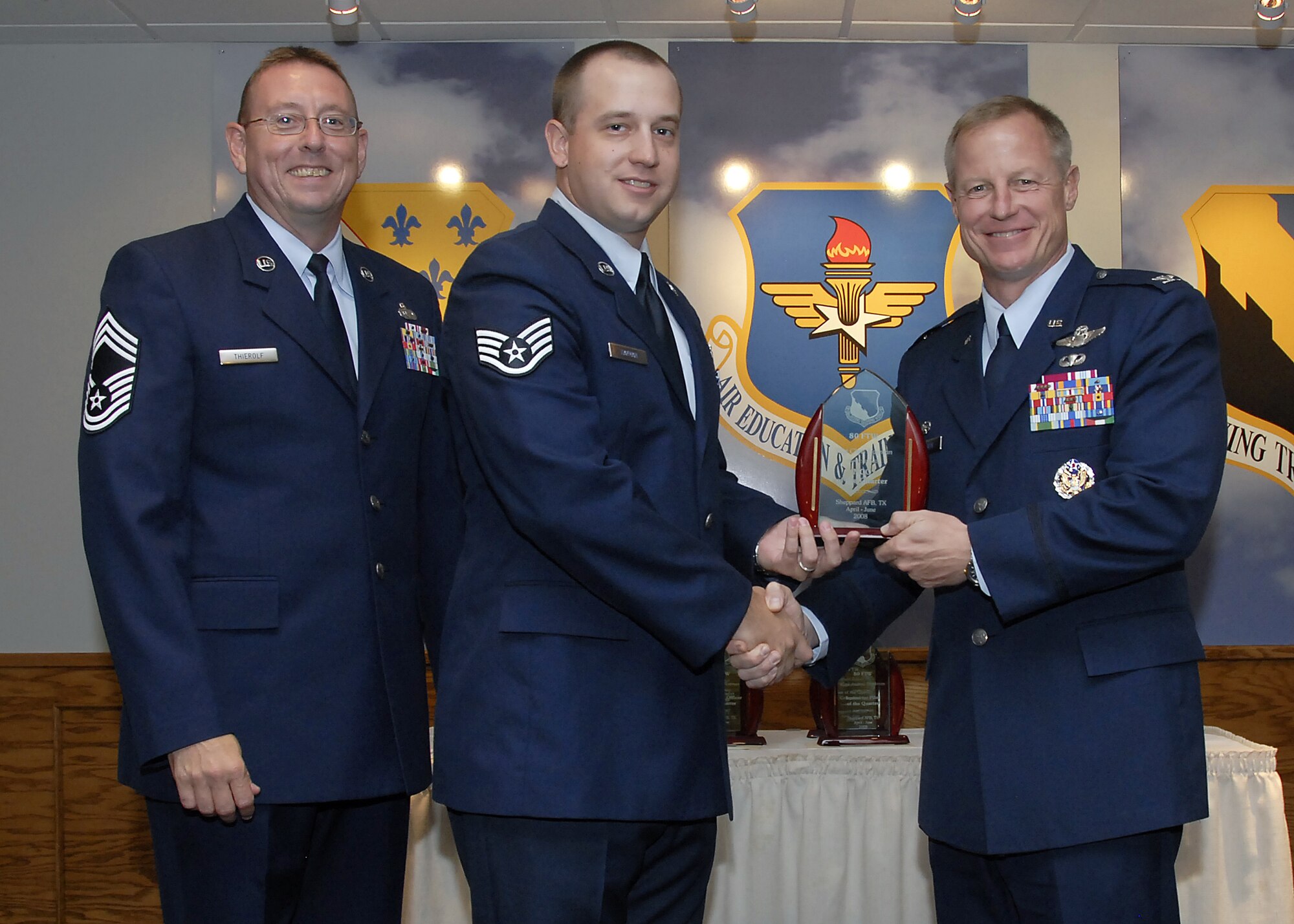 Staff Sgt. Christopher Hayman, center, accepts the Noncommissioned Officer of the Quarter award from 80th Flying Training Wing Commander David Petersen July 22 at the wing's quarterly awards banquet. Also pictured is wing Superintendent Chief Master Sgt. Norman Thierolf. (U.S. Air Force photo/Mike Litteken)