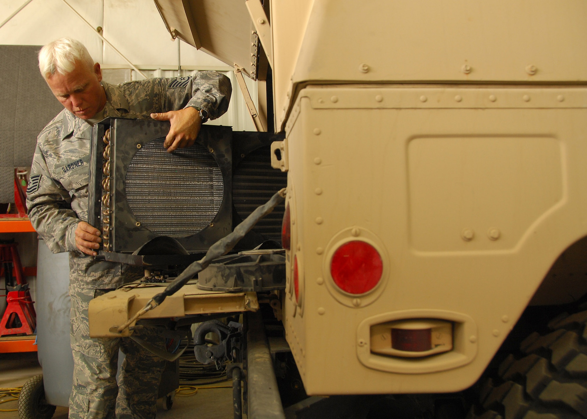 Tech. Sgt. Paul Gardner prepares to install a modified air-conditioning fan and condenser in a Humvee July 21 at a base in Southwest Asia. Sergeant Gardner is credited with the idea of modifying the unit because the Humvees were being brought in continuously for air-conditioning maintenance. He created a specially made L-shaped bracket for the assembly and replaced smaller mounting nut and bolt hardware with larger sizes. Sergeant Gardner is assigned to the 386th Expeditionary Logistics Readiness Squadron. (U.S. Air Force photo/Tech. Sgt. Raheem Moore)