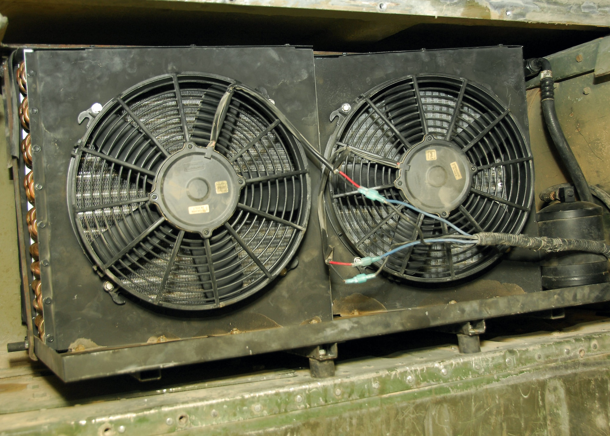 Pictured is a modified air-conditioning fan and condenser in a M1116 Humvee at a base in Southwest Asia July 21. Tech. Sgt. Paul Gardner is credited with the idea of modifying the unit because the Humvees were being brought in continuously for similar air-conditioning maintenance. He created a specially made L-shaped bracket for the assembly and replaced smaller mounting nut and bolt hardware with larger sizes. Sergeant Gardner is assigned to the 386th Expeditionary Logistics Readiness Squadron. (U.S. Air Force photo/Tech. Sgt. Raheem Moore)