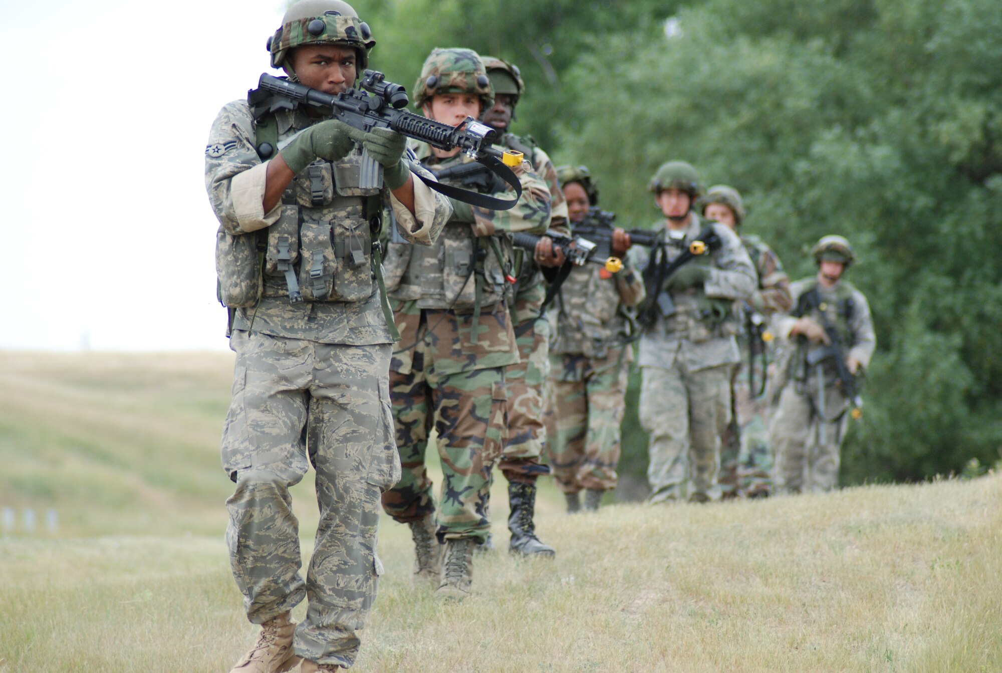 A security forces team marches through simulated hostile terrain near the base Famcamp area during the training session July 17.