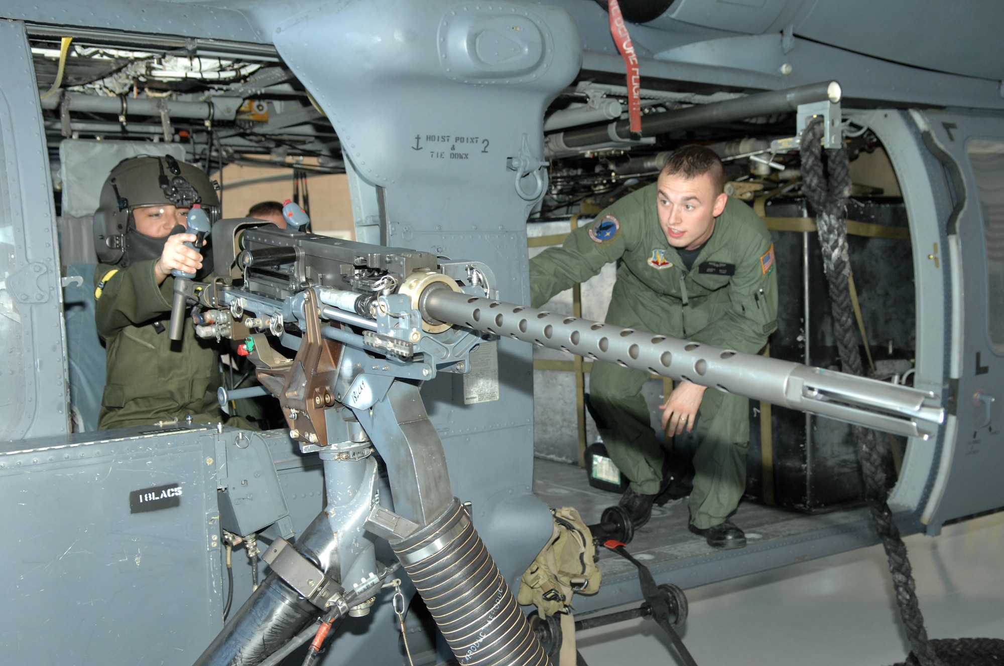 Staff Sgt. Jason Stitt, 55th Rescue Squadron aerial gunner, shows Andrew Valdez, 13 years old, the .50 caliber gun on the side of an HH-60 Pave Hawk during Andrews visit to D-M on July 25. (U.S. Air Force photo/Senior Airman Noah R. Johnson) 