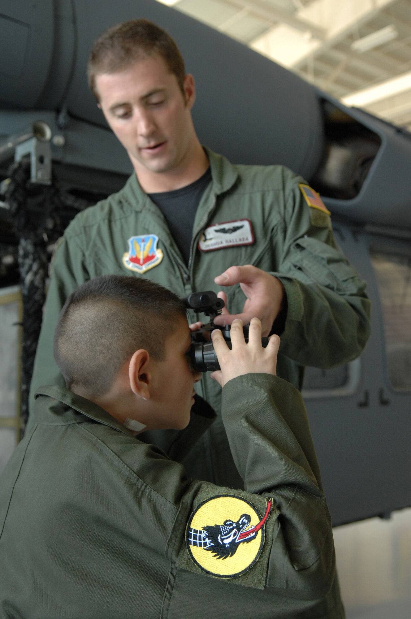 Capt. Joshua Hallada, 55th Rescue Squadron HH-60 pilot, shows 13-year-old Andrew Valdez night vision goggles during Andrew's visit to D-M on July 25. U.S. Air Force photo/Senior Airman Noah R. Johnson)