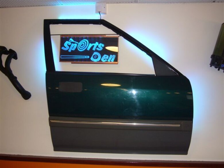 A car door refurbished with bold LED lighting is the signature feature of the Sports Den in the newly dedicated 423rd Air Base Group Dormitory renovation and morale project.  Dorm Manager Air Force Technical Sgt. Phillip Allen who created the Sports Den, found the door at a local dump.  (U.S. Air Force photo by Technical Sgt. Phillip A. Allen)