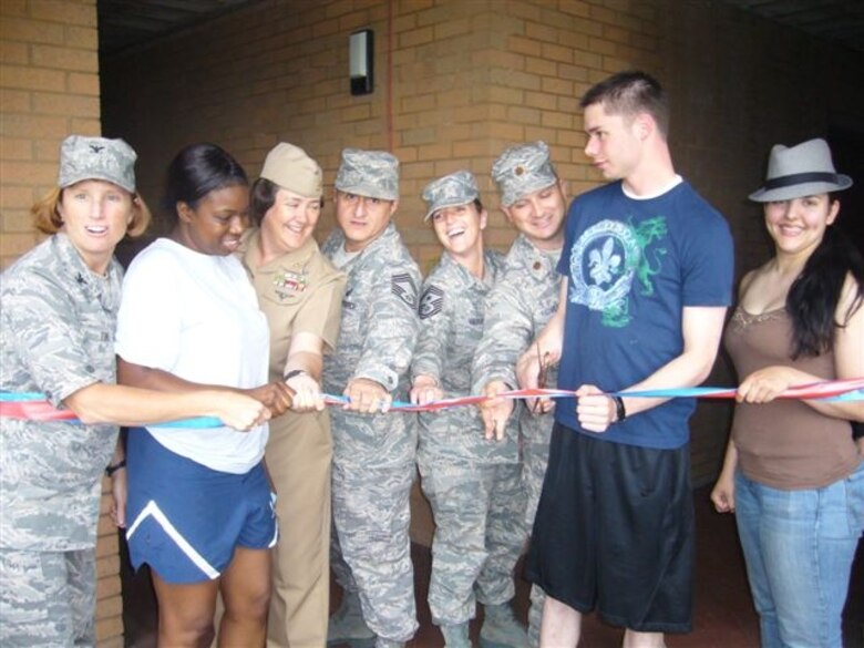 Air Force Colonel Kimberly K. Toney, Commander, 501st Combat Support Wing joins other 501st CSW, JIOCEUR Analytic Center, and 423rd Air Base Group leaders and dorm residents at the dedication of the 423rd Air Base Group Dormitory renovation and morale project.  The renovation features a Sports Den created by Dorm Manager Air Force Technical Sgt. Phillip Allen.  Joining Col Toney is  Senior Airman Latasha D. Bethea, a dorm resident who works at the JAC; JAC Senior Enlisted Leader, Navy Master Chief Shelly A. Wall; 423rd Air Base Group Superintendent Chief Master Sgt. Ronald D. Schwarting II; 501st Combat Support Wing Command Chief, Chief Master Sgt. Maria D. Vaughn; 423rd Civil Engineering Squadron Commander Air Force Major Eric P. Hoversten; an unidentified dorm resident, and Navy Petty Officer Third Class Paula M. Parnacott of the JAC  (U.S. Air Force Photo by Technical Sgt. Phillip A. Allen)