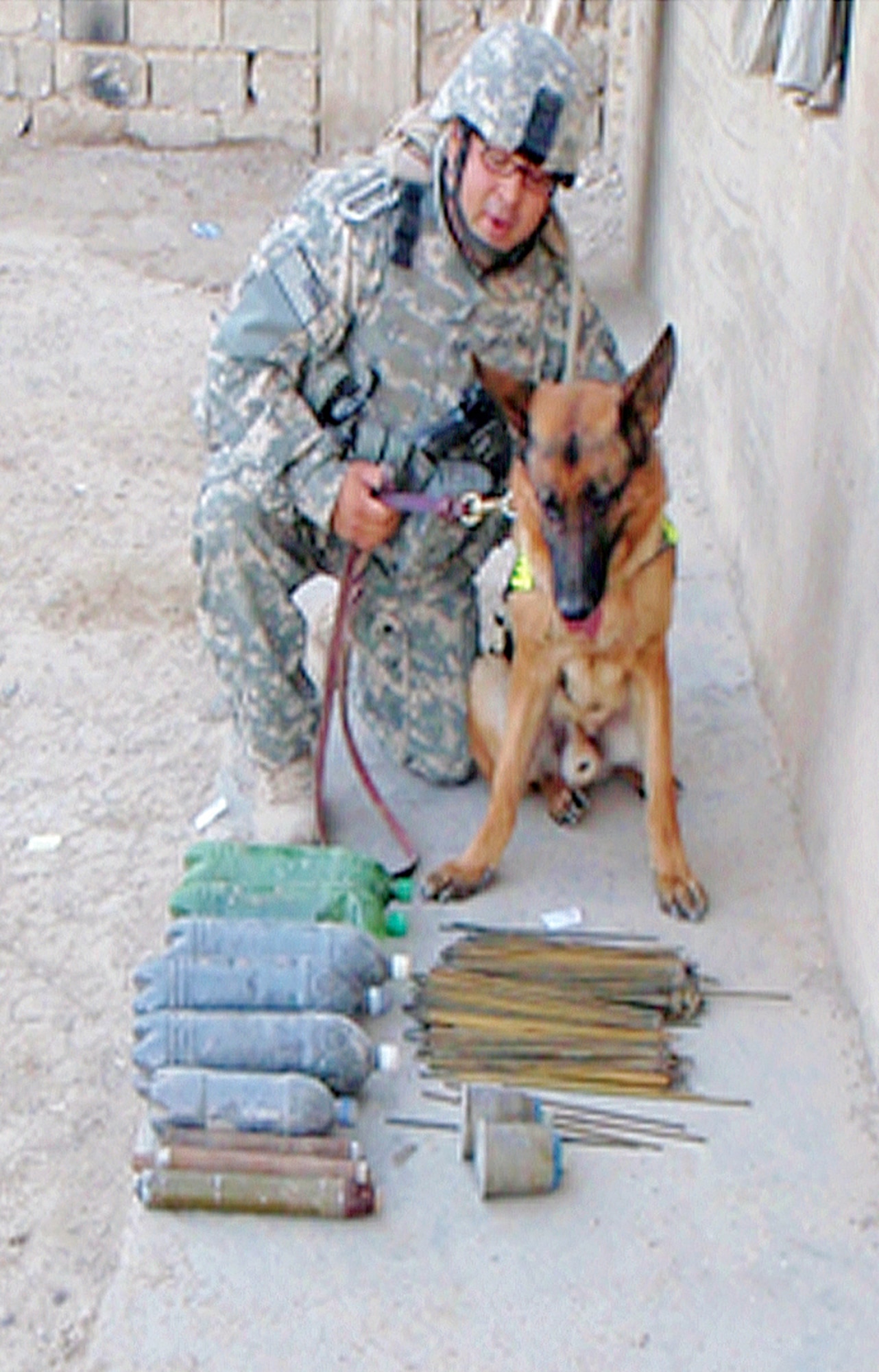 While searching an open area, military working dog Wisum indicated an explosive device on an engine block in the far left corner of the court. A search of the area by the unit discovered one 107mm rocket sitting behind the engine block. While searching the vehicles on the left side of the building, MWD Wisum indicated explosives in a vehicle. Handler Staff Sgt. Raymond Castro notified the unit and a search of the area revealed three cheese charges, six bottles of rocket propellant and three rockets. All devices were secured and taken to be destroyed. A six-foot leash was used during all searches. Courtesy photo.