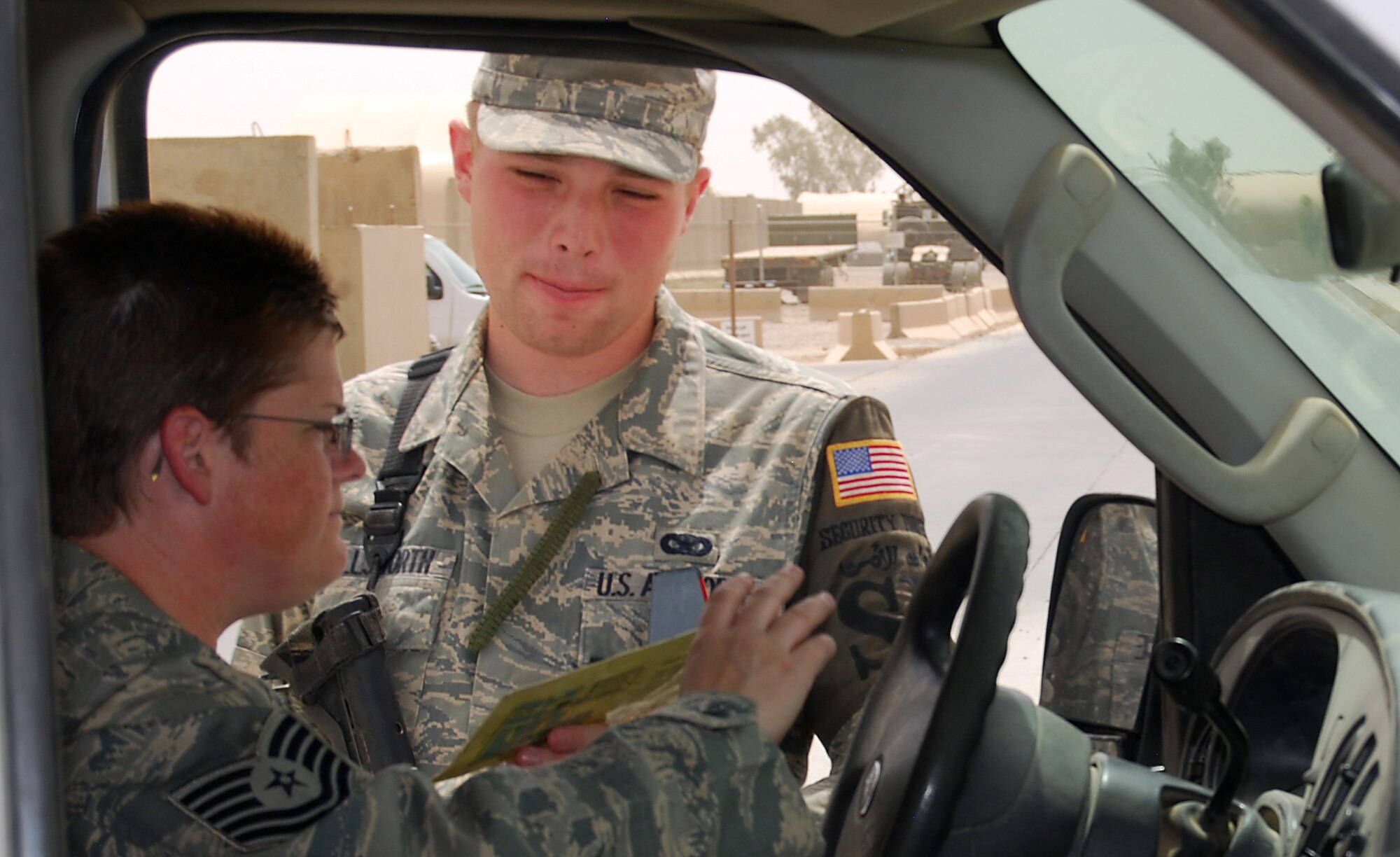 JOINT BASE BALAD, Iraq -- Airman 1st Class Kyle Ellsworth issues a temporary vehicle pass to Tech. Sgt. Jennifer Kane at the Housing 6 Entry Control Point here July 28. The newly activated 332nd Expeditionary Security Forces Group will assume responsibility for entry control points, the badging office, law enforcement and other inside- and outside-the-wire missions pertaining to base defense. Airman Ellsworth, a security forces apprentice with the 332nd Expeditionary Security Forces Squadron here, is deployed from Royal Air Force Lakenheath, England. Sergeant Kane is deployed from Hancock Field Air National Guard Base in Syracuse, N.Y. (U.S. Air Force photo/Staff Sgt. Don Branum)