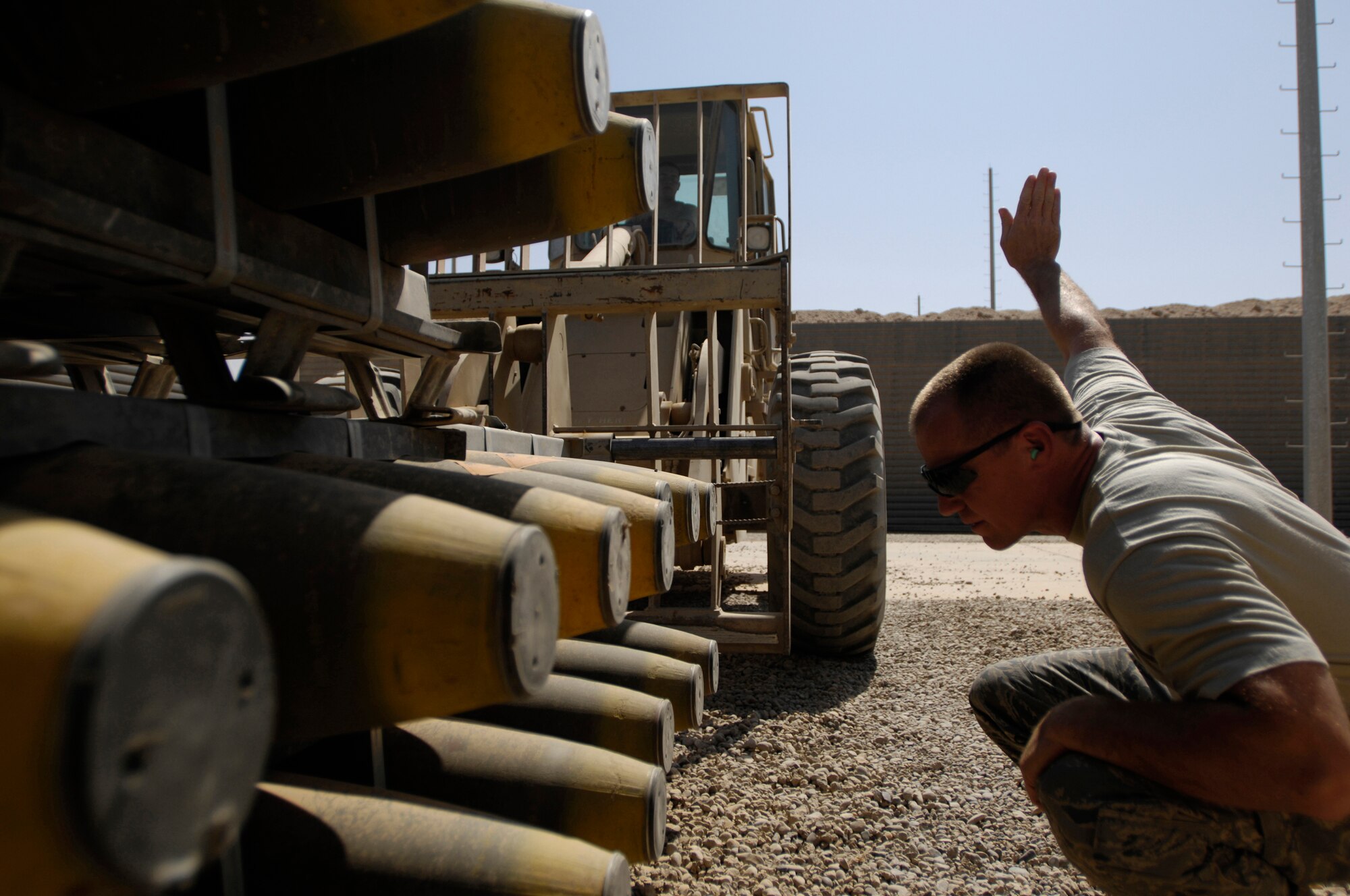 JOINT BASE BALAD, Iraq -- Staff Sgt. Todd Slate guides an all-terrain forklift driven by Airman 1st Class Jesse Carlin to pick up several general purpose bombs here July 24. The bombs' components are stored in different secure areas until they are needed for assembly. The munitions movement team is responsible for storing and transporting the bombs. Both Sergeant Slate and Airman Carlin are assigned to the 332nd Expeditionary Maintenance Squadron. Sergeant Slate is deployed from Hancock Field Air National Guard Base in Syracuse, N.Y., and Airman Carlin is deployed from Shaw Air Force Base, S.C. (U.S. Air Force photo/Airman 1st Class Jason Epley)