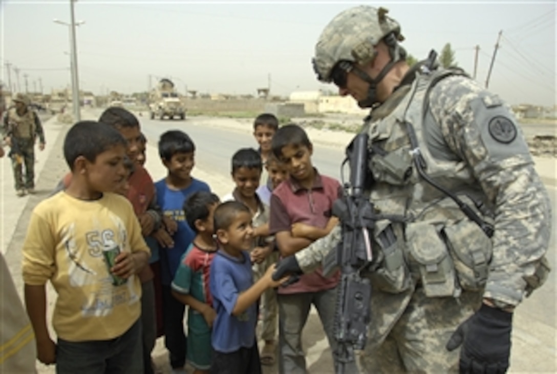 U.S. Army Capt. Karcher from 3rd Battalion, 5th Brigade Combat Team, 2nd Division Military Transition Team speaks with an Iraqi boy in the neighborhood of Somer in Mosul, Iraq, on July 21, 2008.  