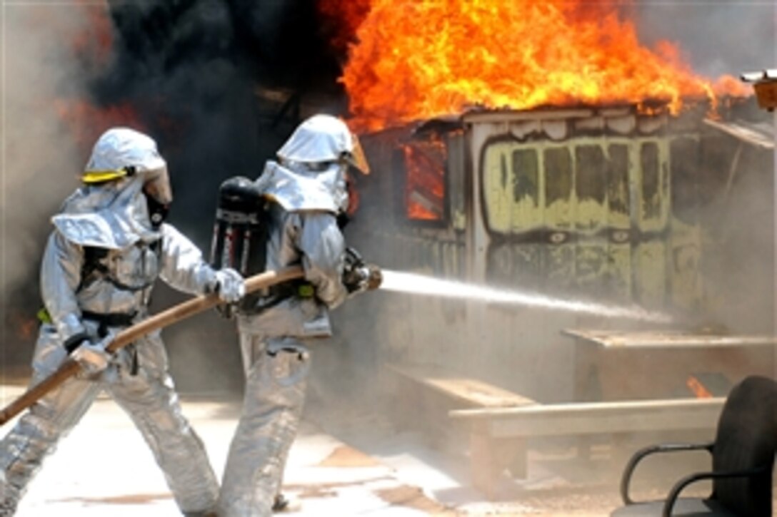 U.S. Air Force firefighters battle to control a blaze that destroyed six metal-framed buildings used as workspace, storage and living quarters at Joint Base Balad, Iraq, July 22, 2008. No injuries were reported from the fire, but a high temperature of 117 degrees forced three firemen to be treated at the Air Force Theater Hospital for heat -related injuries. 