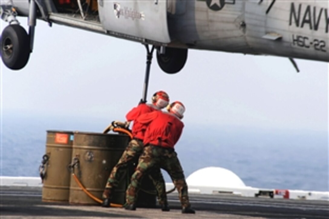 U.S. Navy aviation ordnancemen aboard the aircraft carrier USS Theodore Roosevelt hook ammunition to an MH-60S Seahawk assigned to the "Sea Knights" of Helicopter Sea Combat Squadron 22 during a vertical replenishment at sea with the Military Sealift Command fast combat support ship USNS Supply, Atlantic Ocean, July 23, 2008. 