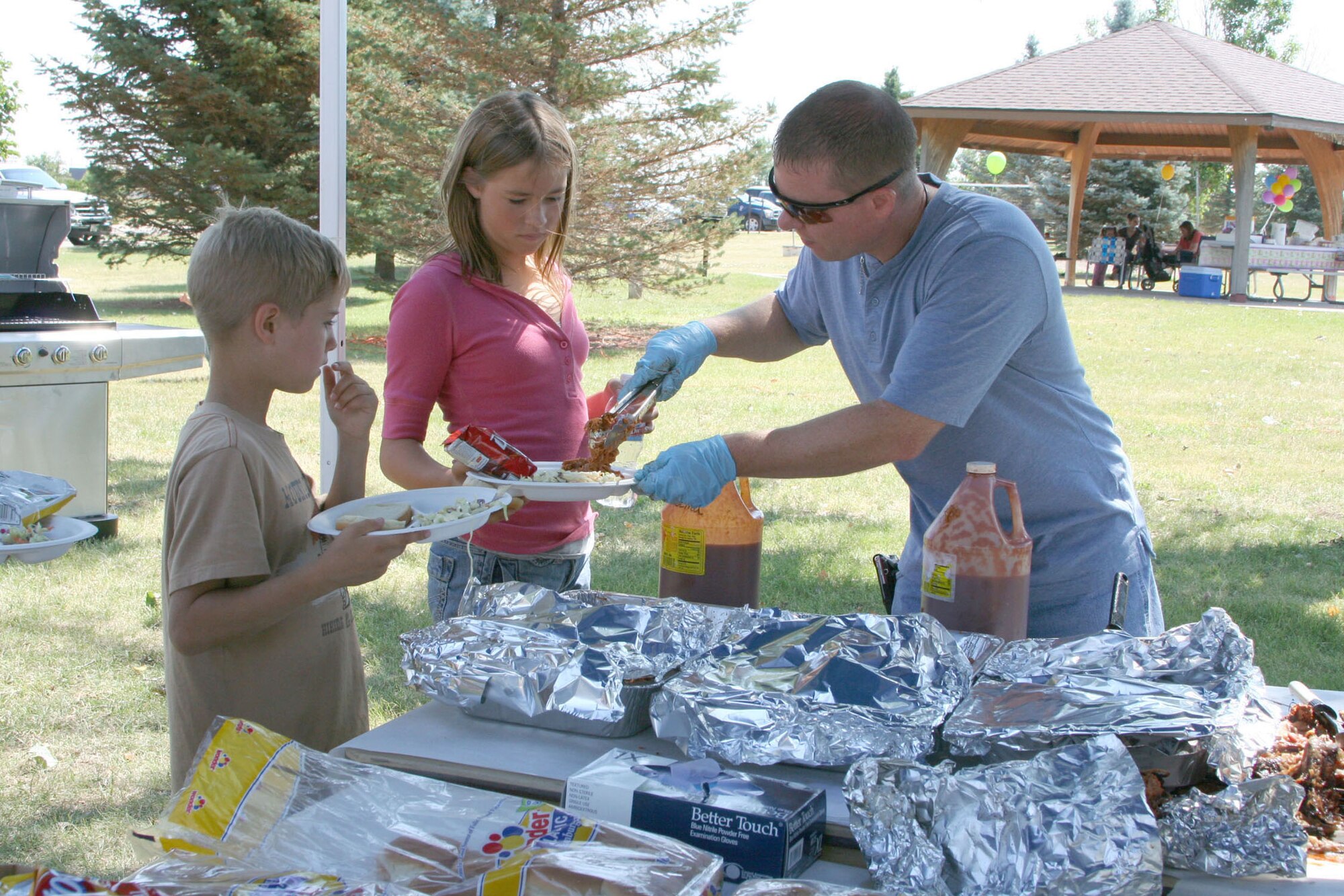 Master Sgt. Roger Wilhelm, 819th RED HORSE Squadron, serves up some smoked, pulled pork to a couple of picnic goers at the Air Force Sergeants Association picnic July 26 at Sun Park Plaza.  The AFSA Chapter 1156 hosted a free pig roast and family picnic featuring music, an inflatable obstacle course and a barbeque grill raffle which raised more than $680 for the chapter. (U.S. Air Force photo/Senior Airman Eydie Sakura)