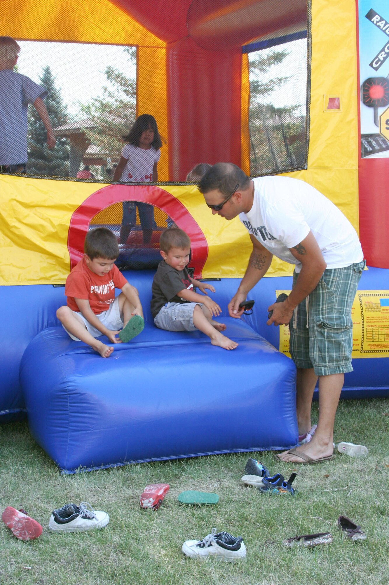 Bridger, 4, and Bostin, 2, get help with their shoes from Staff Sgt. Chris Coleman, 341st Force Support Squadron, after spending time on a bouncy castle at the Air Force Sergeants Association picnic July 26 at Sun Park Plaza.  The AFSA Chapter 1156 hosted a free pig roast and family picnic featuring music, an inflatable obstacle course and a barbeque grill raffle which raised more than $680 for the chapter. (U.S. Air Force photo/Senior Airman Eydie Sakura)