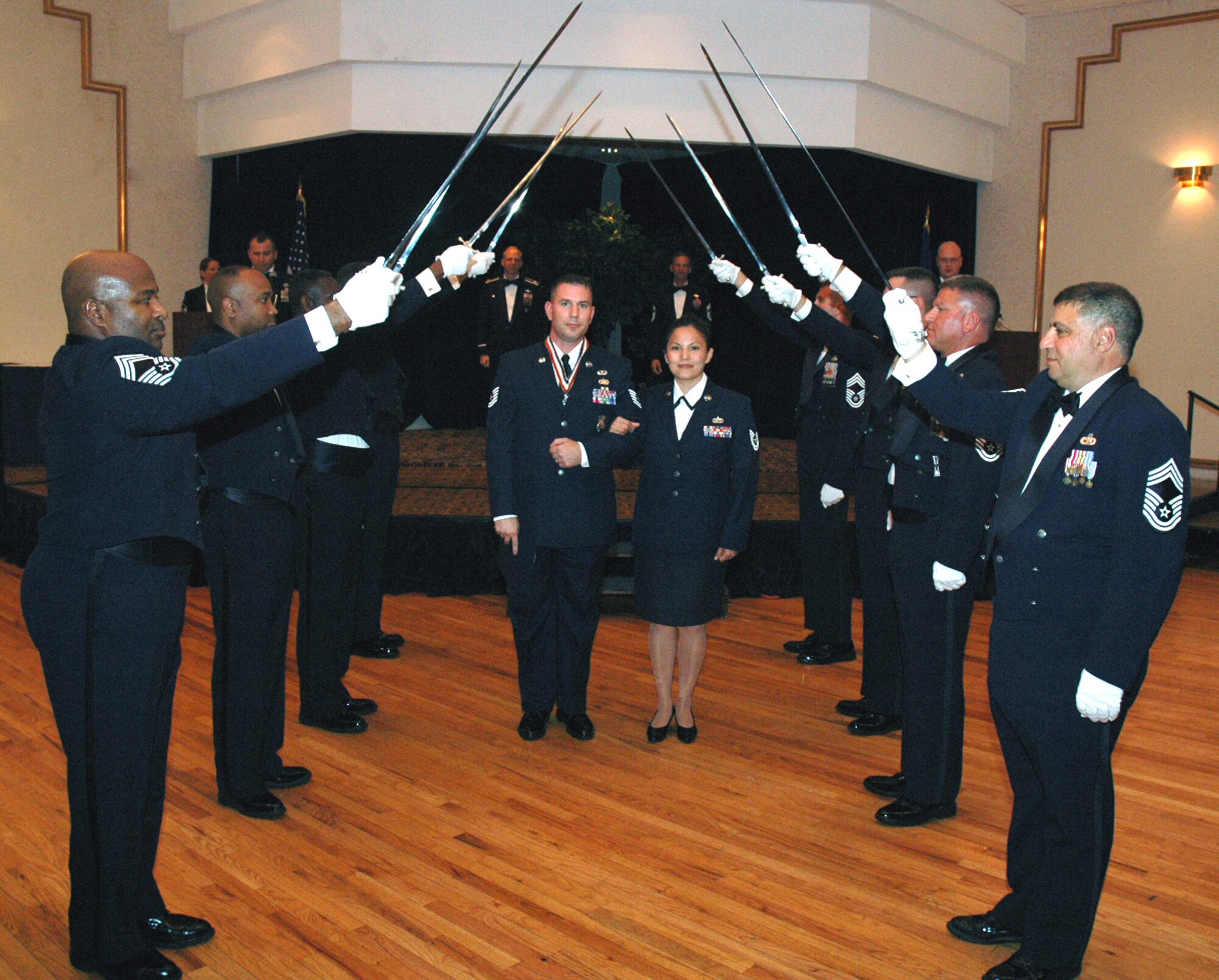 Tech. Sgt. Todd Cooper and his wife, Tech. Sgt. April Cooper, pass under the saber cordon during the 2008 McGuire Senior NCO Induction Ceremony July 25 at the McGuire Air Force Base, N.J., Club.  More than 40 technical sergeants were recognized during the ceremony for being selected for master sergeant and their eventual inclusion into the Air Force senior NCO corps.  Tech. Sgt. Todd Cooper is from the U.S. Air Force Expeditionary Center's 421st Combat Training Squadron on Fort Dix, N.J., and Tech. Sgt. April Cooper is from McGuire's 305th Air Mobility Wing.  (U.S. Air Force Photo/Tech. Sgt. Scott T. Sturkol)