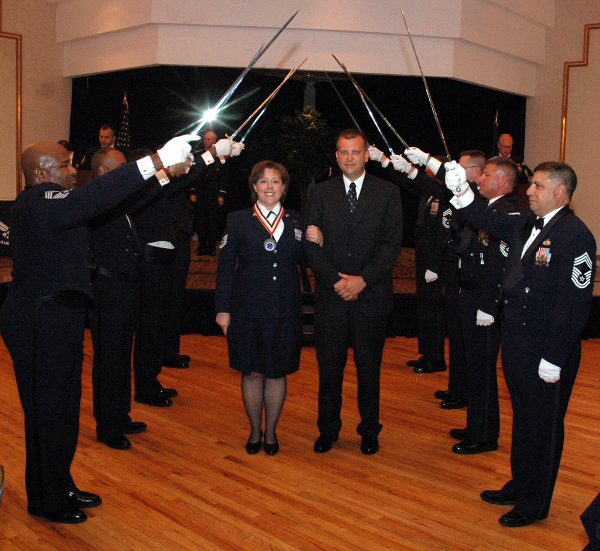 Tech. Sgt. Sue Parker and her husband Chuck pass under the saber cordon during the 2008 McGuire Senior NCO Induction Ceremony July 25 at the McGuire Air Force Base, N.J., Club.  More than 40 technical sergeants were recognized during the ceremony for being selected for master sergeant and their eventual inclusion into the Air Force senior NCO corps.  Sergeant Parker is from the 819th Global Support Squadron.  (U.S. Air Force Photo/Tech. Sgt. Scott T. Sturkol)