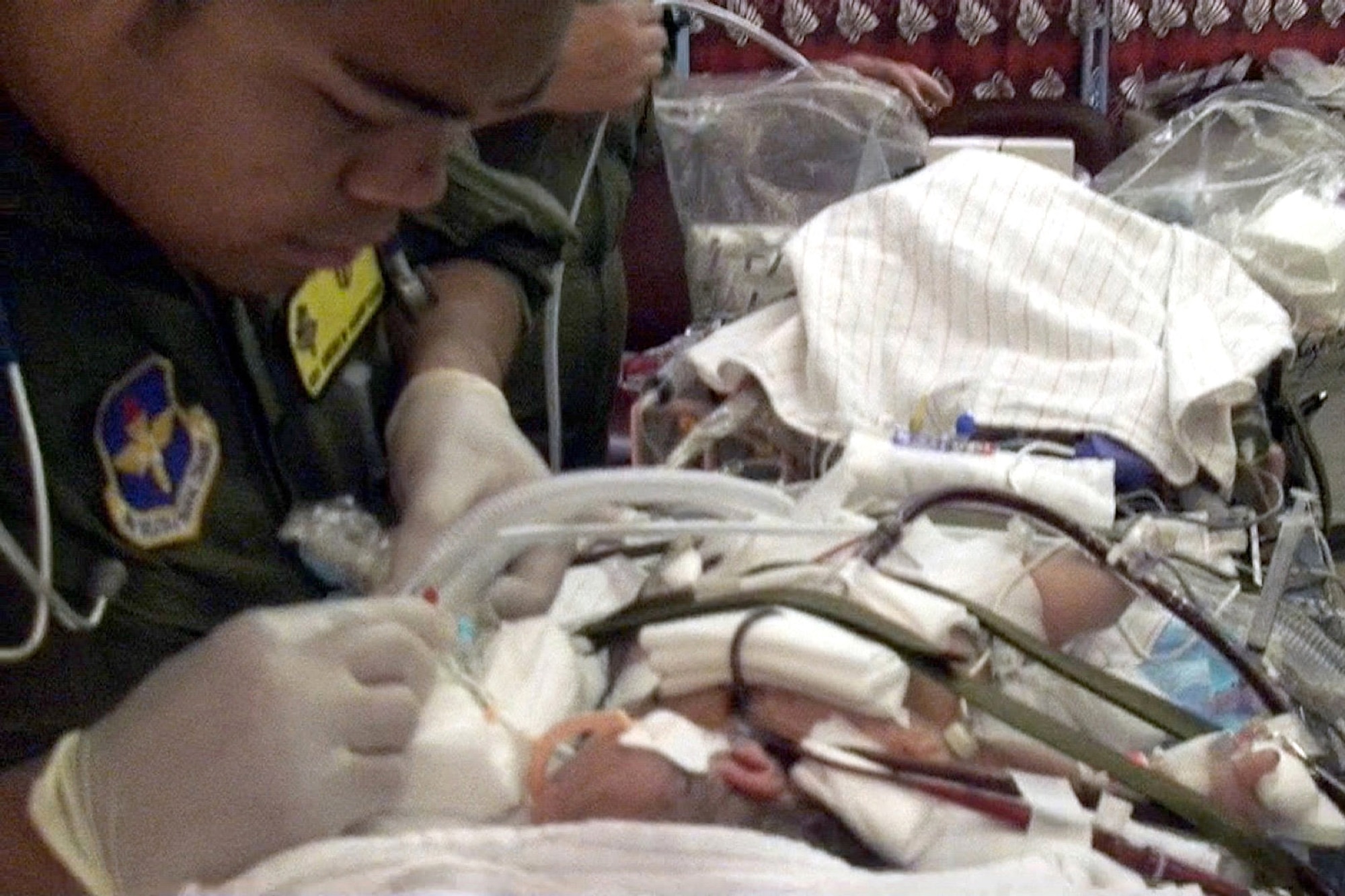 Airman 1st Class Andrew Pamintuan suctions the infant's endotracheal tube on the Wilford Hall Medical Center's extra corporeal membrane oxygenation transport cart in the neonatal intensive care unit at the Kapiolani Medical Center in Honolulu July 22. The ECMO team was needed to transport the critically ill infant to California for advanced medical treatment. Airman Pamintuan is a neonatal intensive care unit respiratory therapist assigned to the 59th Medical Operations Squadron. (U. S. Air Force photo/Maj. Kreangkai Tyree)