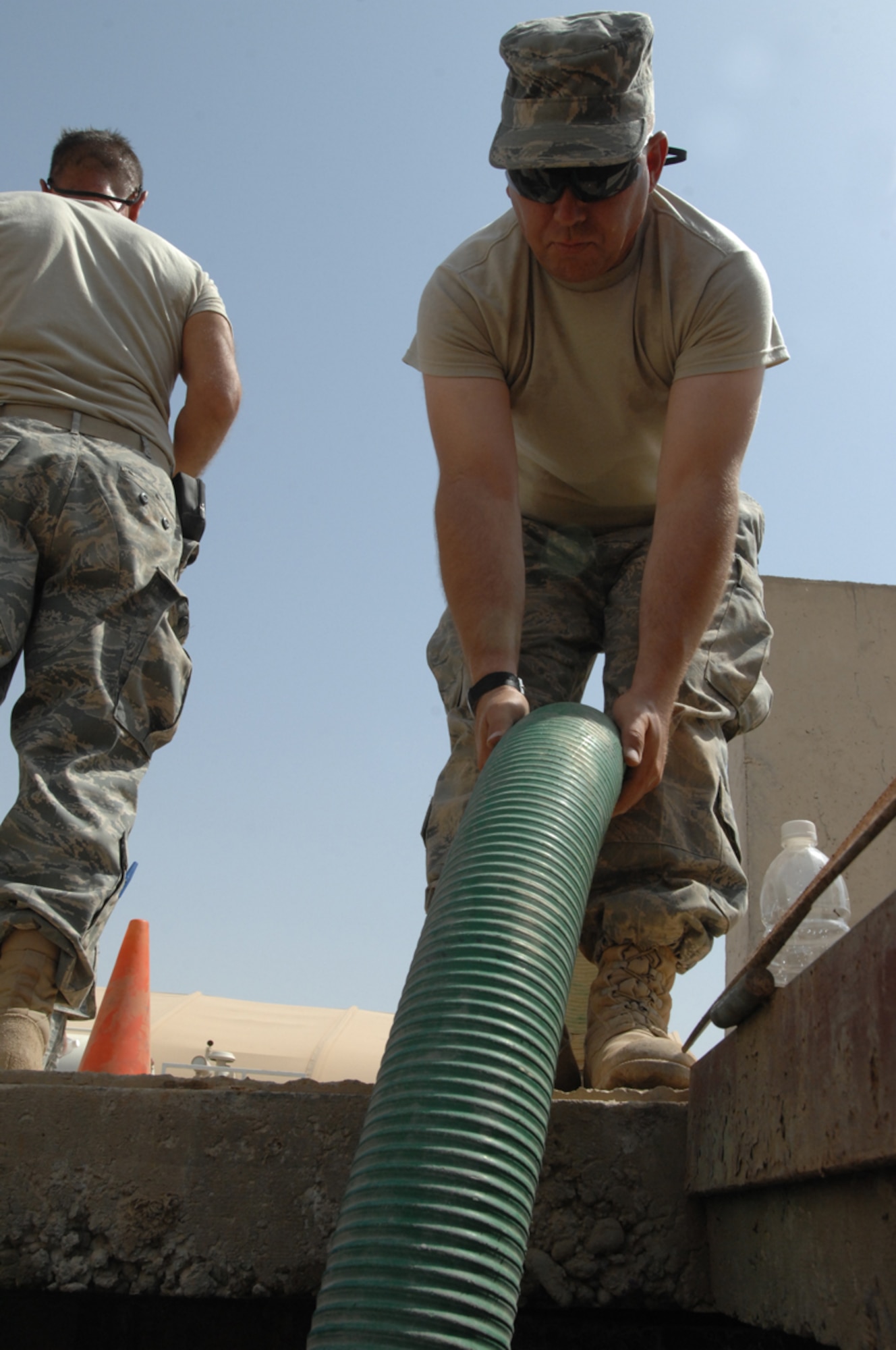 KIRKUK REGIONAL AIR BASE,  Iraq -- Tech. Sgt Timothy Hughes, 506th Expeditionary Civil Engineer Squadron utilities shop, positions a hose to drain a 2,000 gallon holding tank at the water lift station by the Air Force Village laundromat July 29. Both pumps at the lift station failed and the combined efforts of the electrical and utilities shops from the 506 ECES had the lift station operating again in less than 18 hours.  An average of 350 loads of laundry are washed at the laundromat and this station moves the grey water to a larger station prior to being sent to the base's water treatment plant. Sergeant Hughes is deployed here from the 507th Civil Engineer Squadron at Tinker Air Force Base, Okla. (U.S. Photo/Master Sgt. Andrew Leonhard)