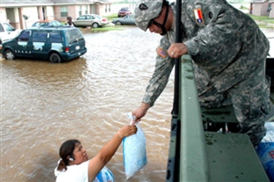 U.S. Army Spc. Timothy C. Berlanga of the Texas Army National Guard hands ice to a resident whose Raymondville, Texas, neighborhood was severely flooded on July 25, 2008, by torrential rain from Hurricane Dolly.
