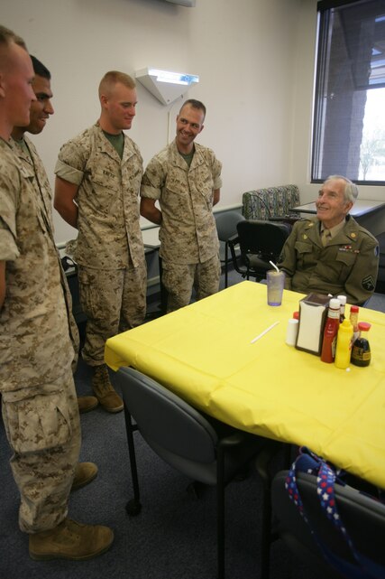 Marines line up to shake the hand of Ivan Glen Speer, an Army veteran who served during World War II at Phelps dining facility Wednesday. Speer was one of the first 18-year-olds to be drafted to go to war.  By the time he hit Omaha Beach, Normandy, France, he was 19 years old, and in charge of a M4 18-ton high-speed tractor, which he named “Hitler’s Crawlin’ Coffin”.