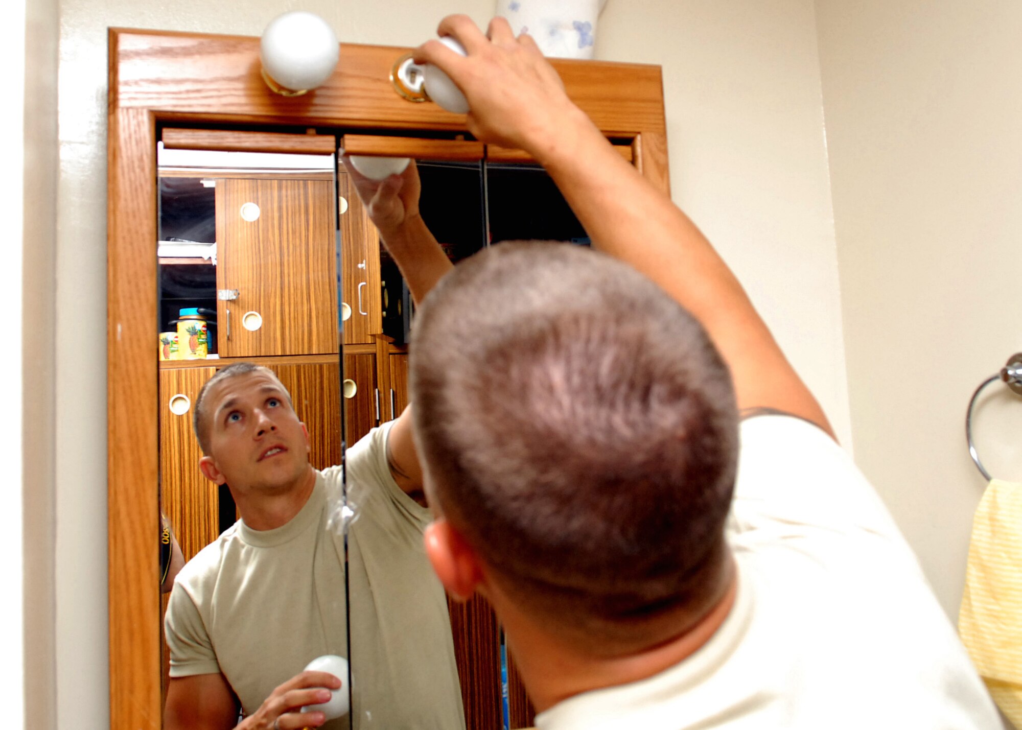 Tech. Sgt. Jeremy Arthur, 718th Civil Engineer Squadron dorm manager , changes light bulbs to new compact fluorescent lights which save money and energy. There are over 500 bulbs total being changed to eco friendly light bulbs in the dorms.  (U.S. Air Force photo/Junko Kinjo)