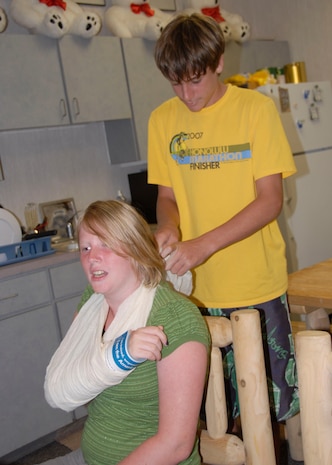 Stephen Still ties a cloth sling around Carey Troxell's neck while practicing a first aid technique at the Outdoor Recreation Center July 26. Stephen, 15, is the son of retired Col. Bernie Still and Carey, 15, is the daughter of Merrill Troxell. (U.S. Air Force photo/Airman 1st Class Cynthia Spalding)