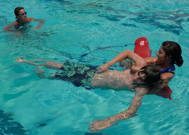 Merrill Troxell inspects Adrionna Pruneda when she acts as the lifeguard while Stephen Still simulates the role of a drowning victim during an active drowning exercise at the base pool July 26. Ms. Troxell is the base's director of outdoor recreation, Stephen, 15, is the son of retired Col. Bernie Still and Adrionna, 15, is the daughter of Master Sgt. Maria Gunther. (U.S. Air Force photo/Airman 1st Class Cynthia Spalding)
