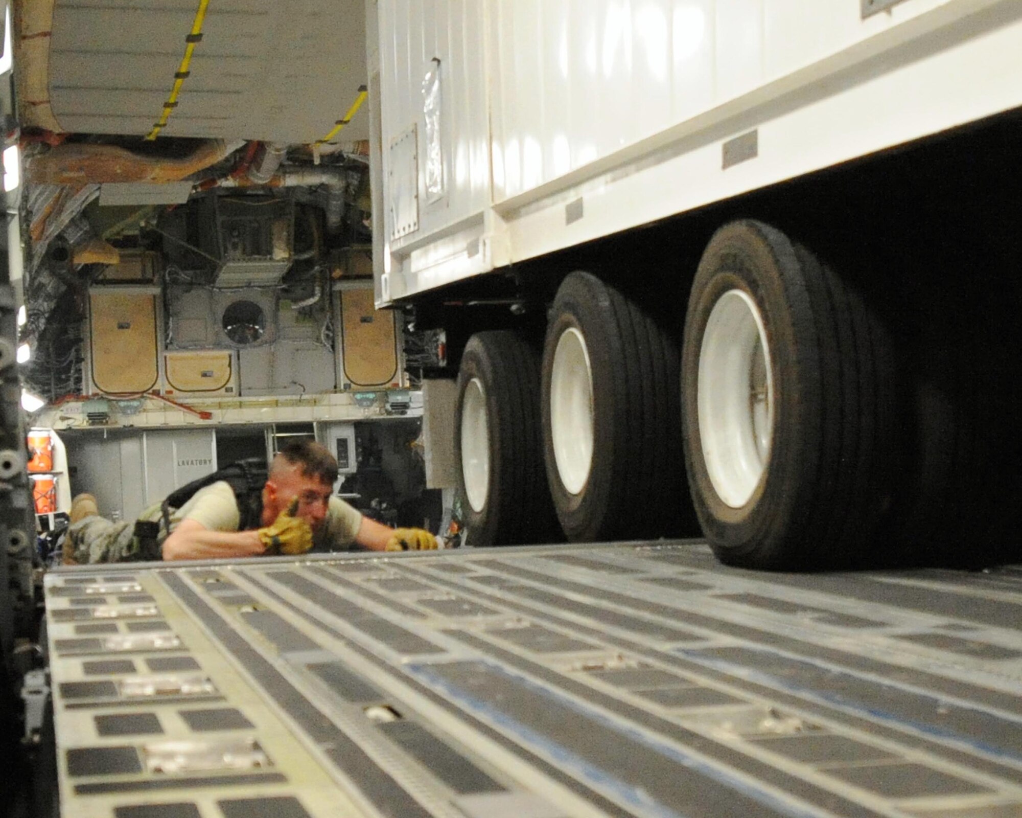 Staff Sgt. Regis Dumm helps guide a new communication trailer out of a C-17 Globemaster III cargo aircraft. The 66-foot, 80,000 pound trailer is one of two recently delivered to Sather Air Base, Iraq, that are designed to provide phone service to the entire Victory Base Complex in Baghdad. Airmen from the 447th Air Expeditionary Group and Soldiers from the 553rd Combat Sustainment Support Battalion joined forces to deliver the massive trailers safely. (U.S. Air Force photo/Master Sgt. Brian Davidson)