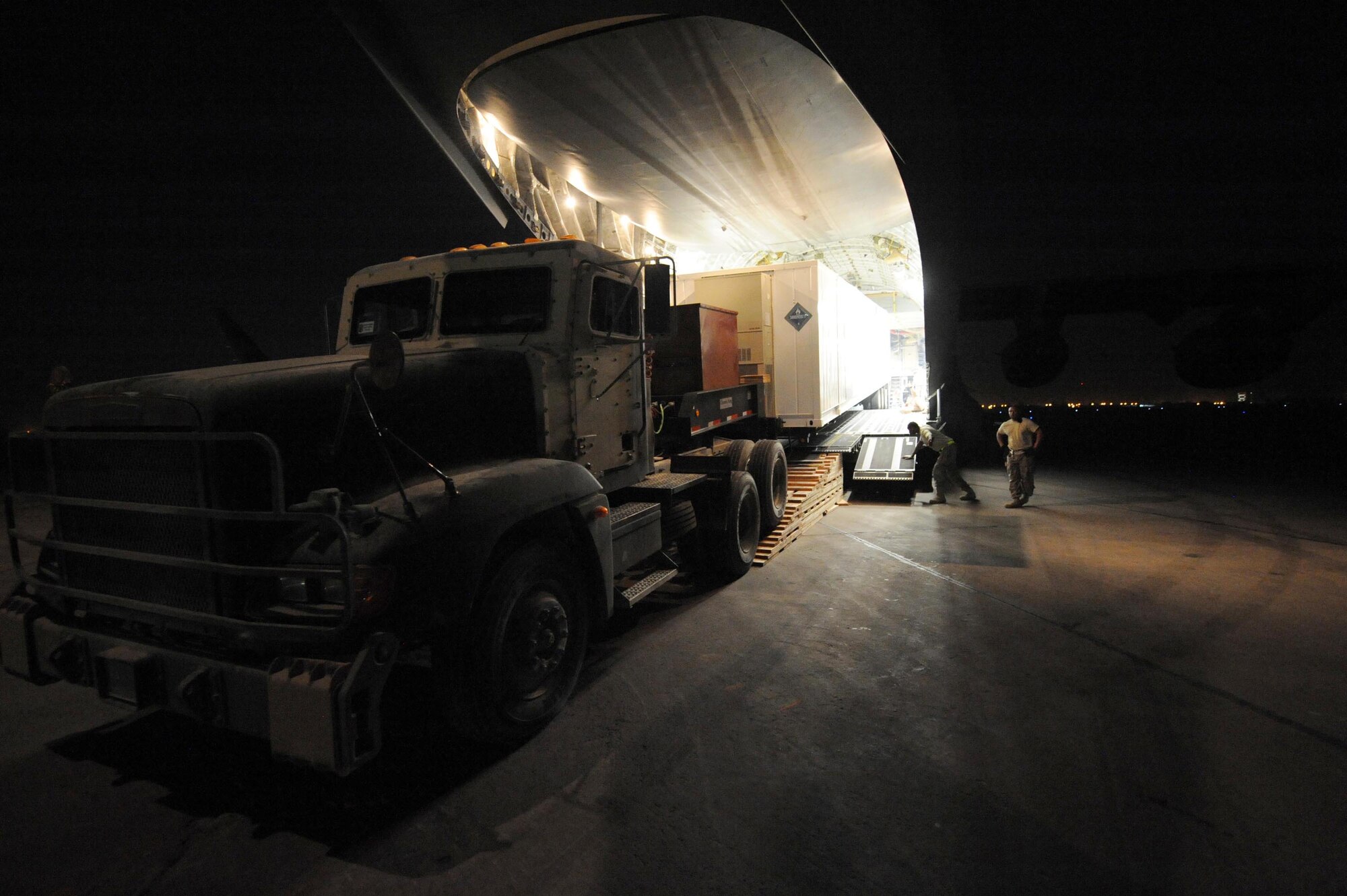A 10-ton armored tractor eases its way out of a C-17 Globemaster III cargo aircraft as it unloads a new communication trailer designed to provide phone service to the entire Victory Base Complex in Baghdad. Airmen from the 447th Air Expeditionary Group and Soldiers from the 553rd Combat Sustainment Support Battalion joined forces to deliver two of the 66-foot, 80,000 pound trailers safely. (U.S. Air Force photo/Master Sgt. Brian Davidson)