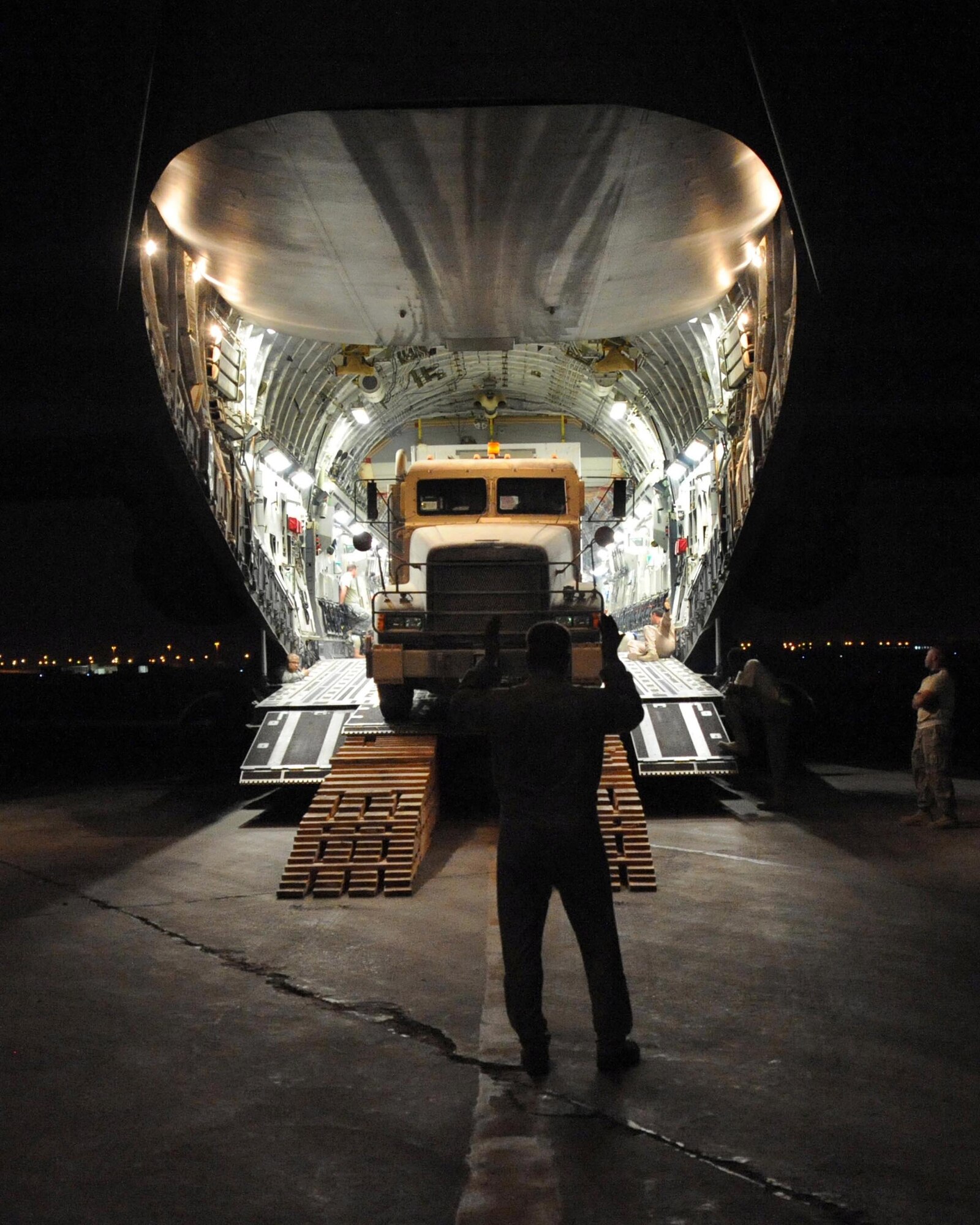 A C-17 Globemaster III loadmaster guides a 10-ton armored tractor as it unloads a new communication trailer designed to provide phone service to the entire Victory Base Complex in Baghdad. Airmen from the 447th Air Expeditionary Group and Soldiers from the 553rd Combat Sustainment Support Battalion joined forces to deliver two of the 66-foot, 80,000 pound trailers safely. (U.S. Air Force photo/Master Sgt. Brian Davidson)

