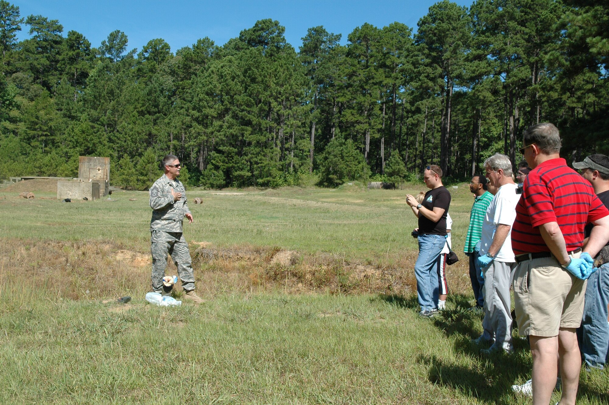 Explosive Ordnance Disposal explains to security scanners as an explosive is detonated a distance from the group.