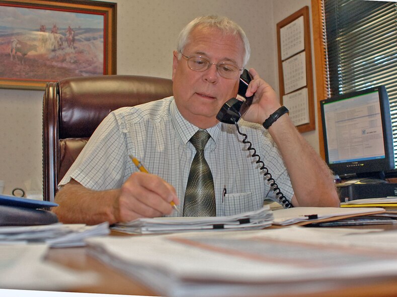 DYESS AIR FORCE BASE, Texas -- Mr. Michael Schultz, deputy base engineer, takes a phone call while working on some paperwork in his office here July 30.  After 33 years of service, Mr. Schultz is packing things up and retiring Aug 1.  He has been one of the cornerstones for the 7th Civil Engineer Squadron and his spent more than 20 years of his federal career here at Dyess.  (U.S. Air Force photo by Senior Airman Felicia Juenke).      