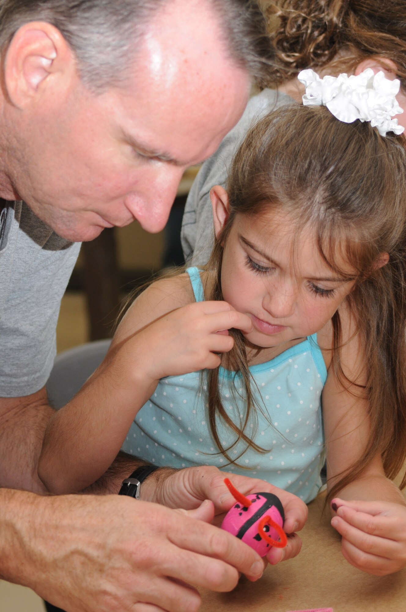 Chaplain (Capt.) David Barns and his 5-year-old daughter, Courtney, work to complete a “bug on wheels” ceramic piece.  Courtney’s mom is Cindy Barns.  (U.S. Air Force photo by Kemberly Groue)