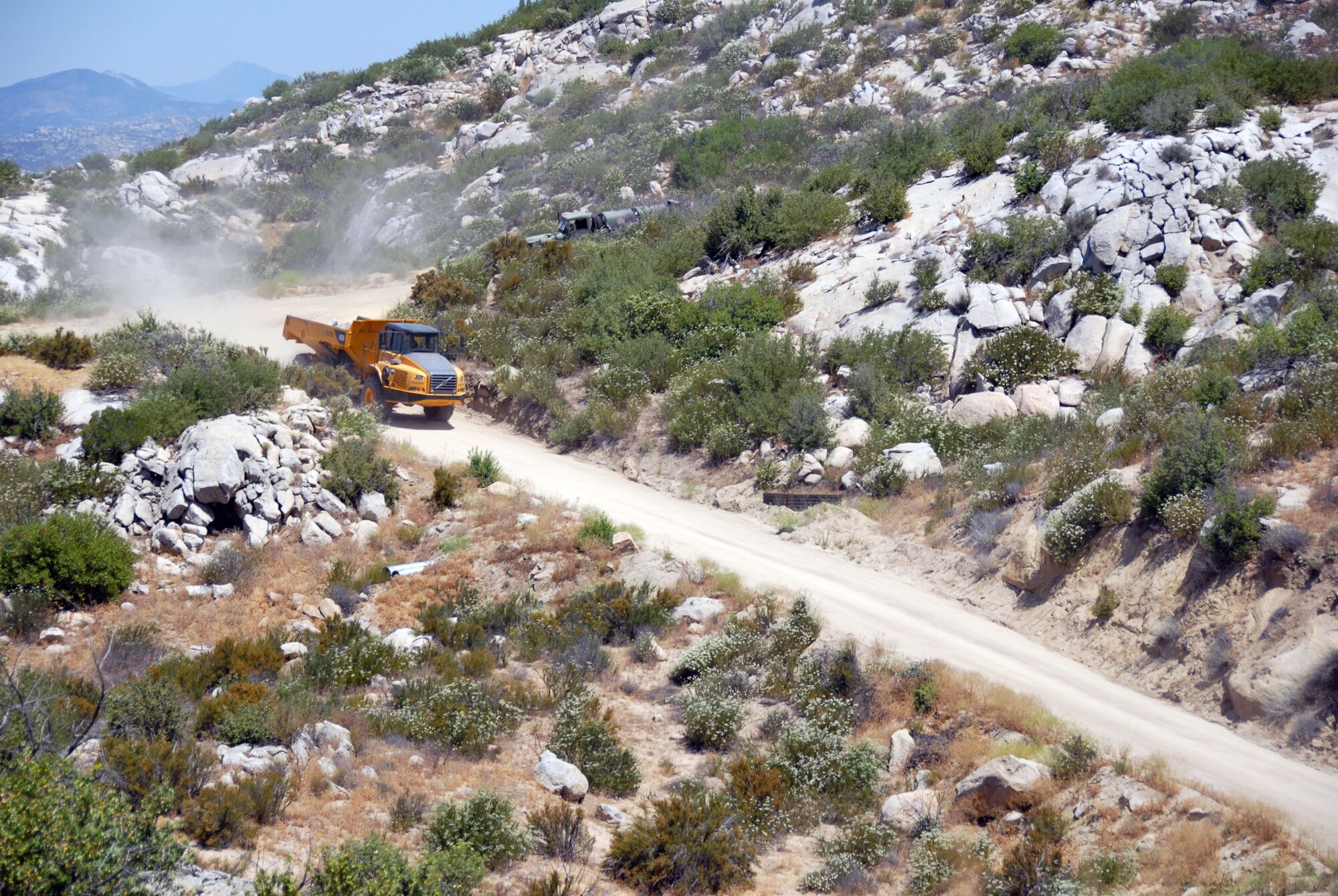 A 32-ton dump truck driven by Master Sgt. Dan Casanova of the 149th Civil Engineer Squadron traverses the mountain road to Smith Canyon with a load of boulders. (Texas Military Forces photo by Tech. Sgt. Gregory Ripps)