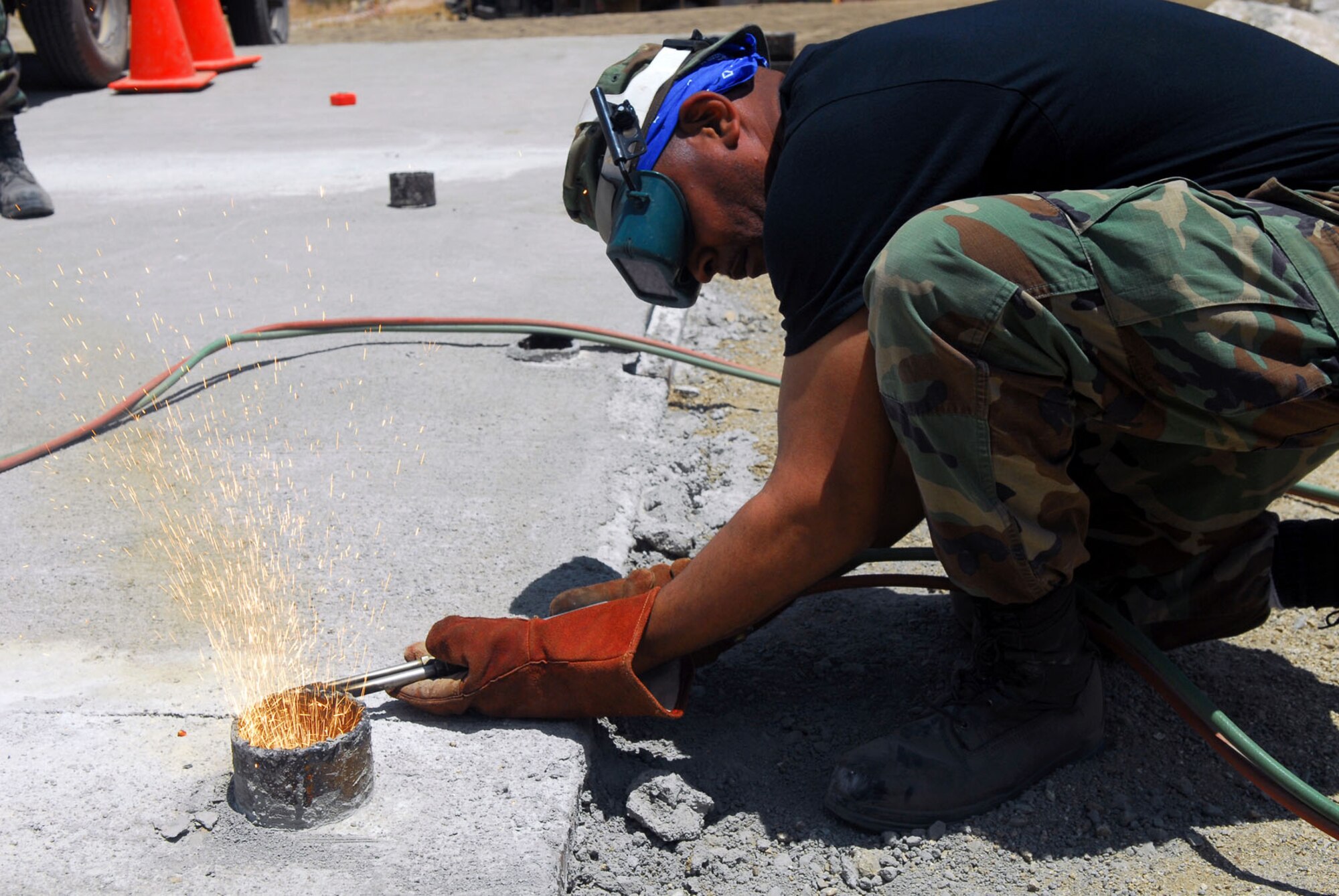 Causing some sparks to fly, Staff Sgt. Marvin Williams of the 149th Fighter Wing Civil Engineer Squadron blow-torches a pipe level with the concrete surface of a water crossing. The unit worked on real-world engineering projects  while simultaneously completing two weeks of training.