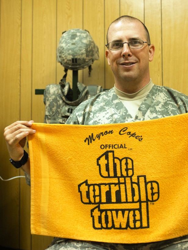 Army Capt. James Hart, a physician assistant for the 10th Mountain Division’s Headquarters and Support Company, Division Special Troops Battalion, holds up a Terrible Towel in his office at a medical aid station on Camp Victory, Iraq. U.S. Army photo by Staff Sgt. Michel Sauret, Multinational Division Center