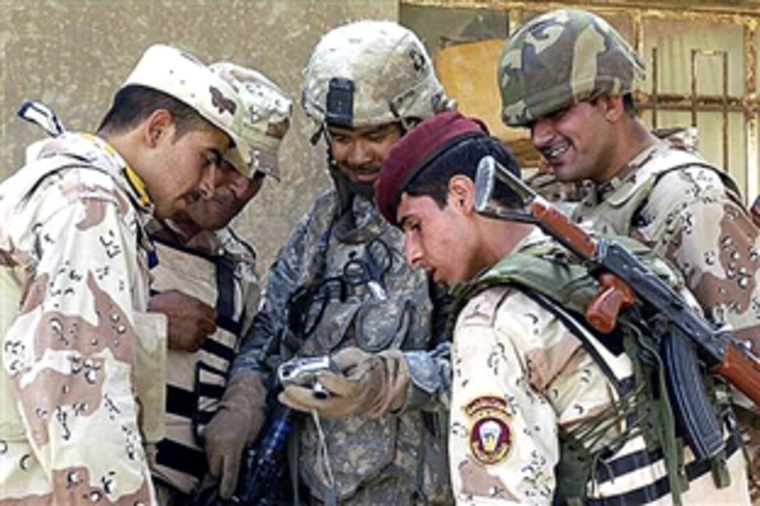 Iraqi army soldiers gather to look at photos taken of them by a U.S. Army soldier as they hand out toys to children in the Al-Jazeera desert in Iraq, July 26, 2008. The soldiers are assigned to 2nd Battalion, 320th Field Artillery Regiment. 
  
