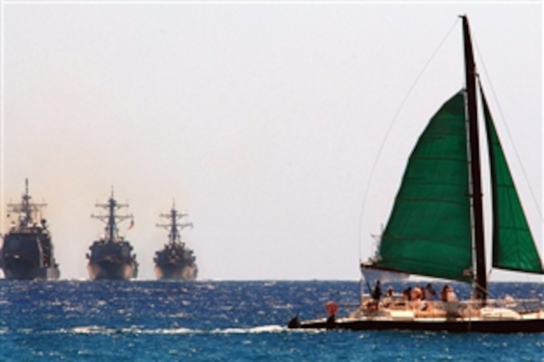 A sailboat crosses in front of the guided missile destroyers USS Pinckney, USS Chung-Hoon and USS Kane as they perform a sail-by near Waikiki Beach to celebrate the centennial of the Great White Fleet, Pearl Harbor, Hawaii, July 29, 2008. The destroyers are participating in Rim of the Pacific 2008, an international exercise.