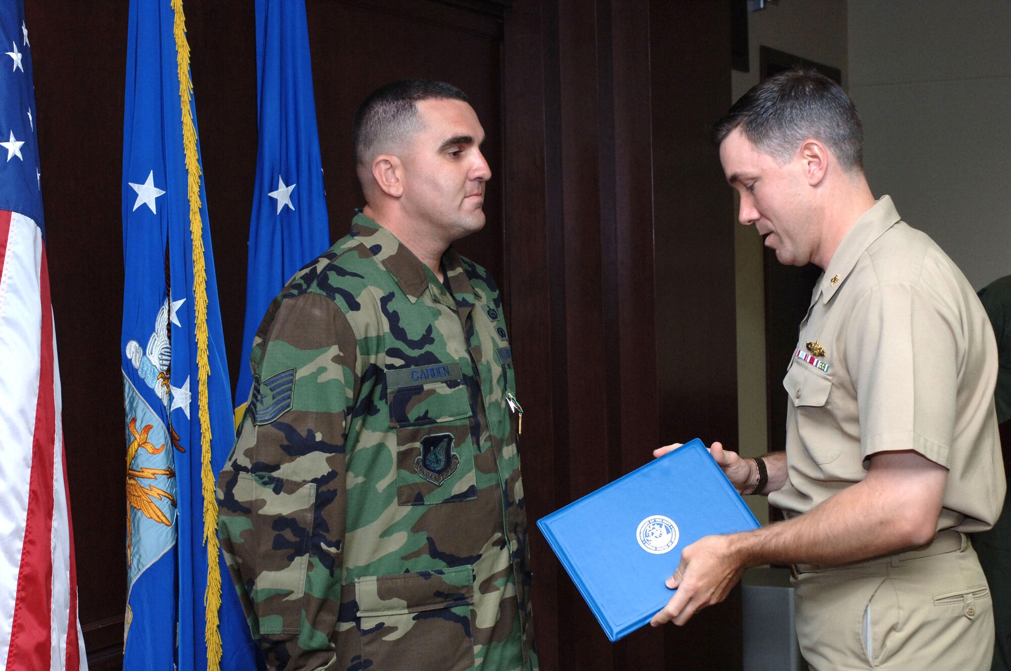 Tech. Sgt. Casey L. Carden (left), 15th Airlift Wing Plans and Programs, stands at attention as Navy Cmdr. Glenn Dietrick, N-4, U.S. Third Fleet Command, presents him with a Navy Achievement Medal for his work during the recent RIMPAC 2008 exercise, in which he acted as a wing liason office for the multi-ntional exercise.