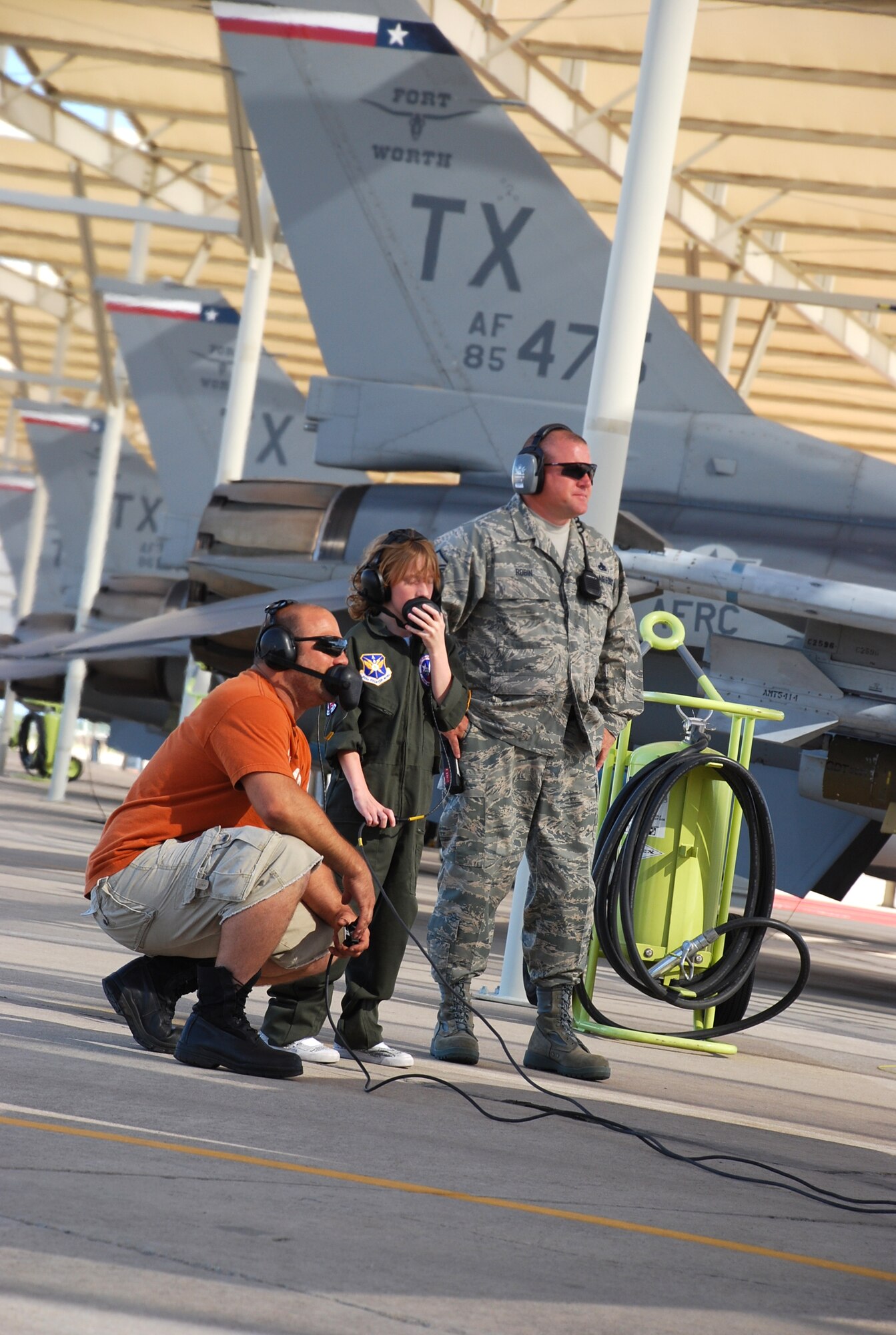 (right to left) Master Sgt. Nate Robin, 301st Aircraft Maintenance Squadron superintendent, assists Tech. Sgt. Scott Pecikonis, 301st AMXS crew chief, with the 301st Fighter Wing's latest Pilot for a Day participant. The "Pilot of the Day" program is an opportunity to have a child with a life-threatening or terminal illness visit the wing in hopes of forgetting, for just one day, their situation. The program has seen six children since it began in 2005. (U.S. Air Force Photo/Tech. Sgt. Julie Briden-Garcia)