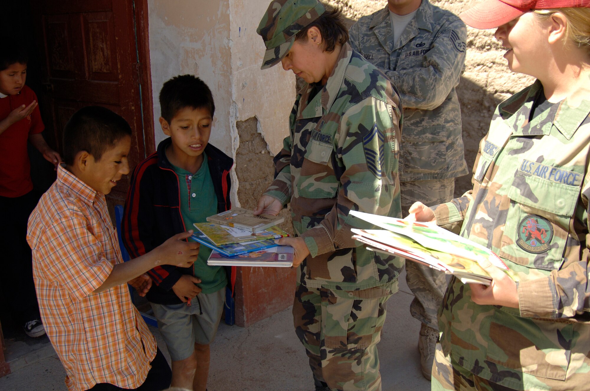Senior MSgt. Teresa Denton-Price, task force MEDRETE liaison officer, left, and Senior Airman Traci Achterberg, a task force personnelist, offer books to Peruvian orphans awaiting medical care at a medical mission in Cobadonga, Peru, July 26.  The medical mission is the fifth of nine being conducted in support of New Horizons - Peru 2008, a Peruvian and U.S. effort to bring humanitarian aid to the region of Ayacucho, Peru.  (U.S. Air Force photo/1st Lt. Mary Pekas)