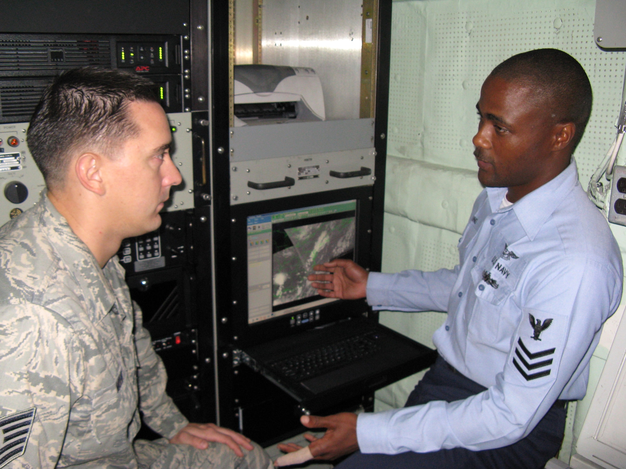 Navy Petty Officer 1st Class Timothy Manning demonstrates how to manipulate satellite pictures on the SMQ-11 satellite receiver to Tech. Sgt. Philip Mohr, weather forecaster. A joint Navy and Air Force weather team worked together at sea aboard the USS Bataan in support of JTFEX 08-4, a multinational exercise that included Sailors, Soldiers, Airmen, Marines and Coast Guardsmen. (U.S. Air Force photo/Capt. Nicholas J. Sabula) 
