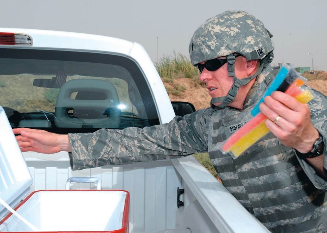 KIRKUK REGIONAL AIR BASE, Iraq - Capt. Andy Thornley, 316th wing Chapel  senior Protestant chaplain, retrieves a handful of posicles from a cooler of popsicles.  Chaplain Thornley and his team go out into Iraq's summer heat with a cooler of popsicles to distribute while providing company to the men and women who defend the air base. (Photo by Tech. Sgt. Jeff Walston)