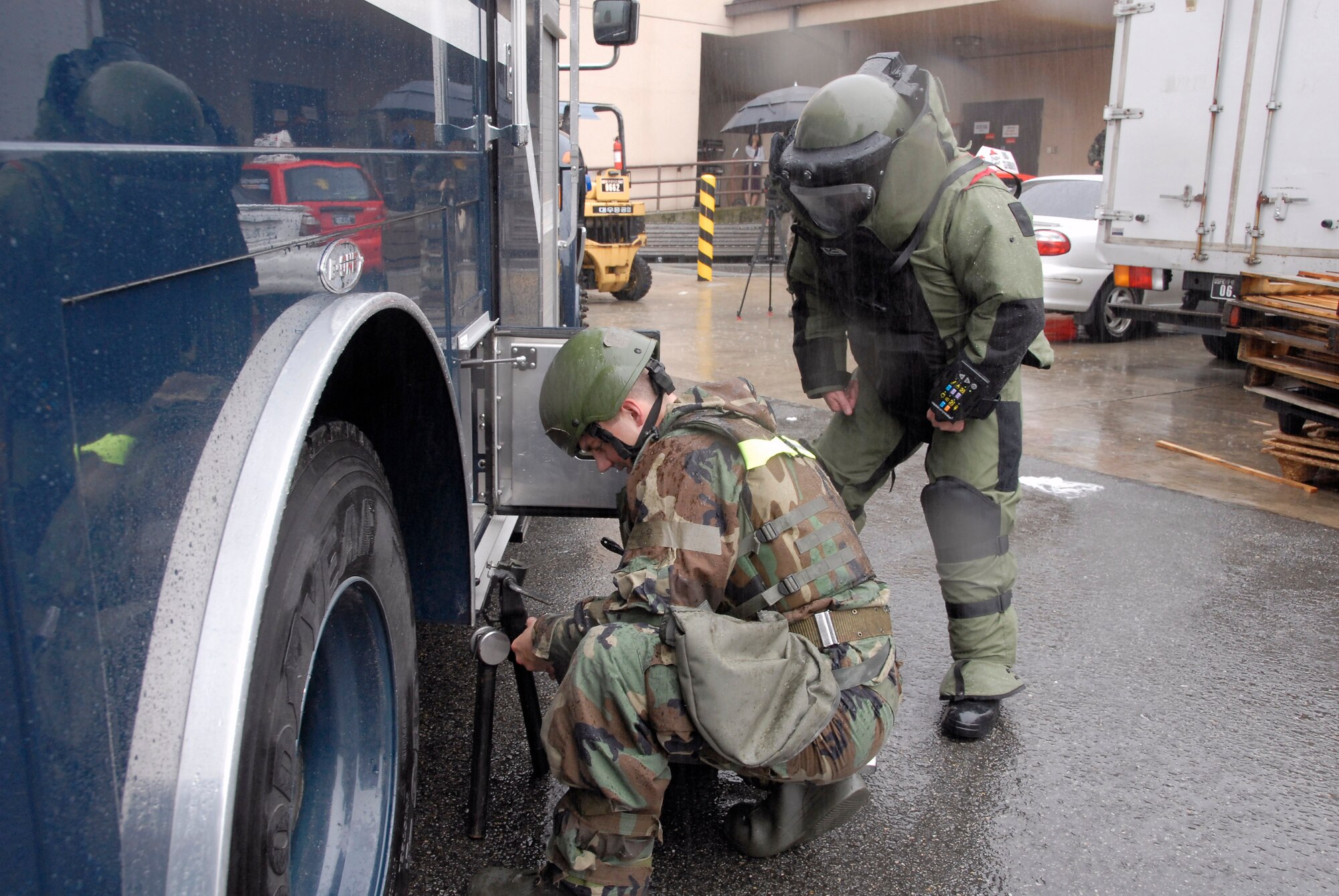 Airman Matthew Morris and Tech. Sgt. Jared Worstell (in bomb suit), explosive ordnance disposal Airmen with the 51st Civil Engineer Squadron at Osan Air Base, South Korea, prepare to use an F6A robot to remove a suspicious package from the base post office during a base-wide exercise July 24.  The robot is equipped with several television cameras for remote viewing and a dexterous arm for hazardous tasks. (U.S. Air Force photo/Staff Sgt. Lakisha Croley)