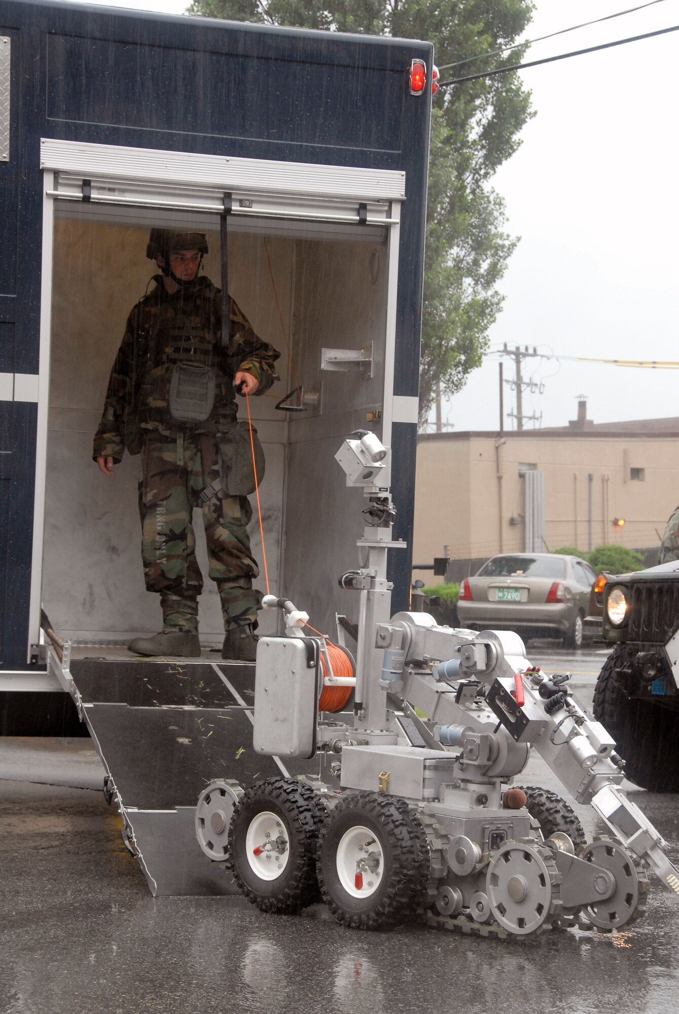 Airman Matthew Morris, an explosive ordnance disposal apprentice for the 51st Civil Engineer Squadron at Osan Air Base, South Korea, guides an F6A robot as it prepares to remove a suspicious package at the base post office July 24 during a base-wide exercise.  The robot is equipped with several television cameras for remote viewing and a dexterous arm for hazardous tasks. (U.S. Air Force photo/Staff Sgt. Lakisha Croley)