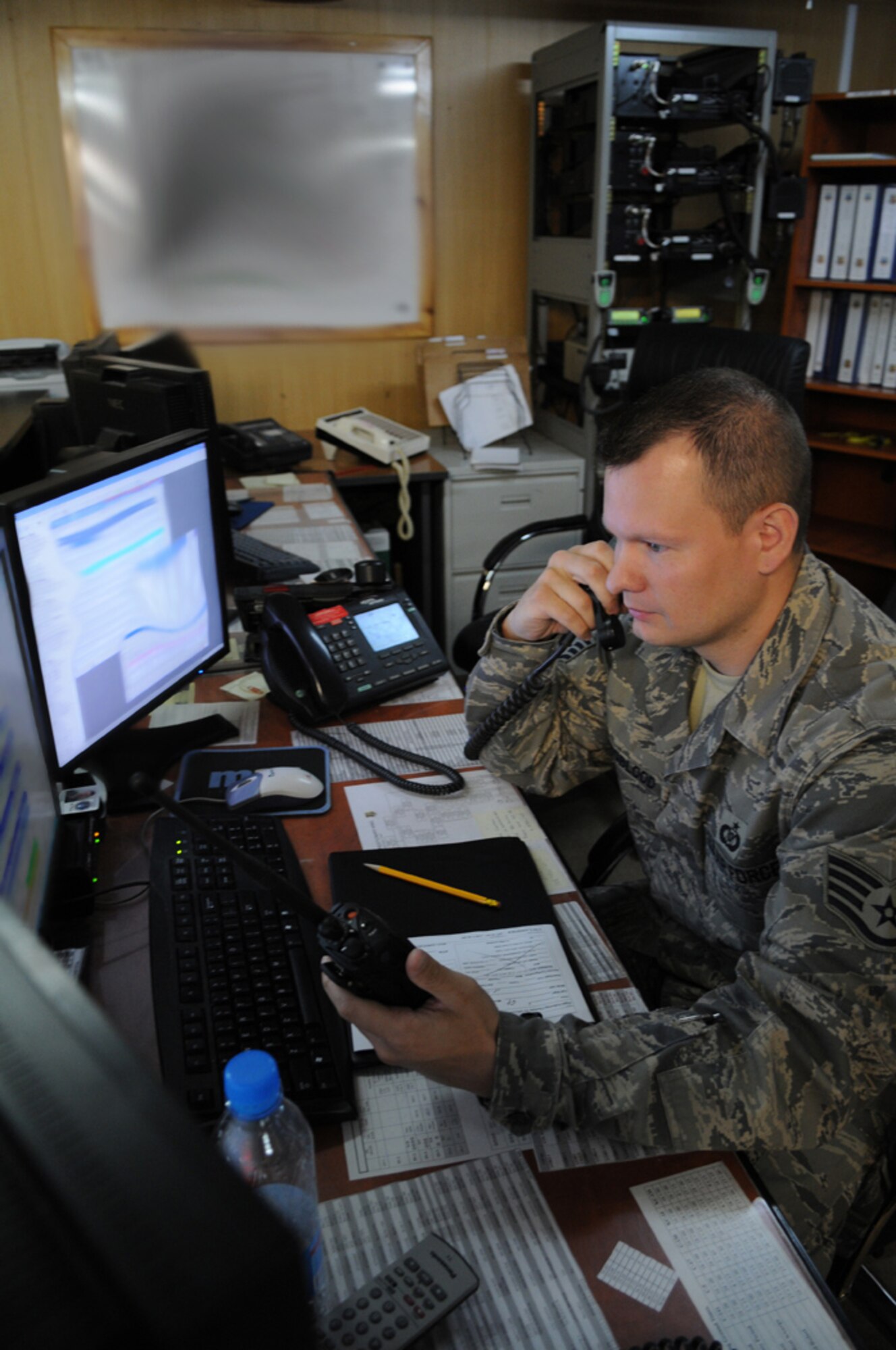 MANAS AIR BASE, KYRGYZ REPUBLIC -- Staff Sgt. Richard Youngblood, 376th Air Expeditionary Wing Command Post controller, takes telephone calls while managing radio traffic here July 28. The Manas Air Base command post serves as the wing's nerve center. Its controllers are responsible for monitoring and tracking emergencies as well as all aircraft sorties taking off and landing at the Kyrgyz Republic air base. (U.S. Air Force photo / Airman First Class Ruth Holcomb)