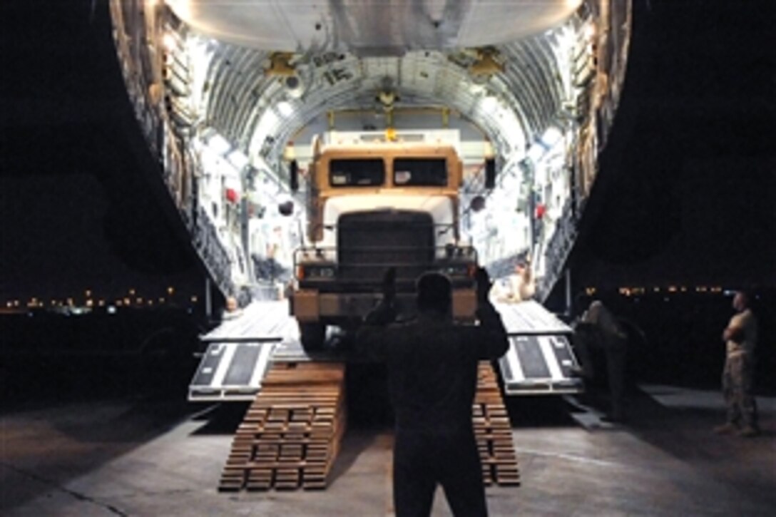 A U.S. Air Force C-17 Globemaster III loadmaster guides a 10-ton armored tractor as it unloads a communication trailer designed to provide phone service to the Victory Base Complex in Baghdad, Iraq, July 28, 2008. Airmen assigned to the 447th Air Expeditionary Group and U.S. soldiers assigned to the 553rd Combat Sustainment Support Battalion delivered two of the 66-foot, 80,000 pound trailers. 