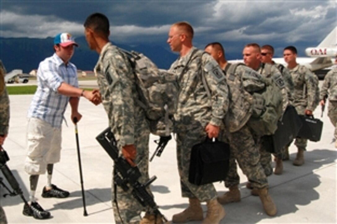 U.S. Army Spc. Jesse A. Murphree, left, greets his 173rd Airborne Brigade Combat Team comrades returning from deployment in Afghanistan, on the flight line at Aviano Air Base, Italy, July 22, 2008. Murphree lost his legs in a roadside bomb attack in the Korengal Valley, near Ali Abad, Afghanistan, Dec. 27, 2007. He has been undergoing treatment at the Walter Reed Army Medical Center. 