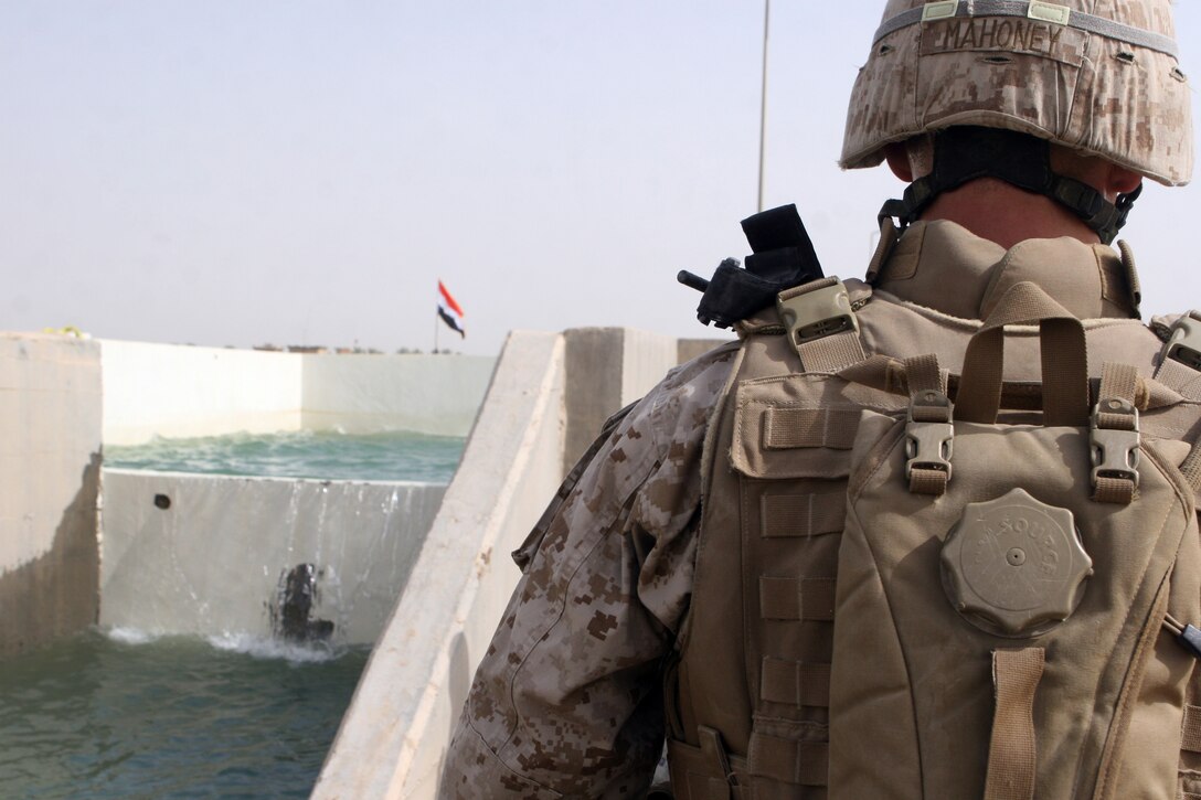1st Lt. Brendan Mahoney, platoon commander, 3rd Platoon, Company G, 2nd Battalion, 3rd Marine Regiment, Regimental Combat Team 1, looks on as Iraqi Police take a swim in the canal July 31, in Lahib, Iraq. The Island Warriors helped reopen a water pump, which will pump clean water to the people of Lahib for their fields and livestock.