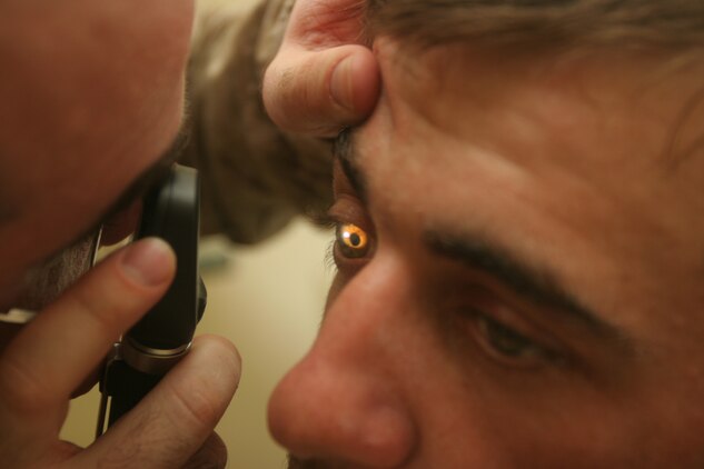 Navy Lt. Cmdr. Lewis J. Fermaglich, medical officer for 2nd Low Altitude Air Defense Battalion, 1st Marine Logistics Group, examines an Iraqi man’s eye during a cooperative medical engagement on July 31. The purpose of the CME was to increase the quality of life for residents here and to further develop and improve relationships with the locals.